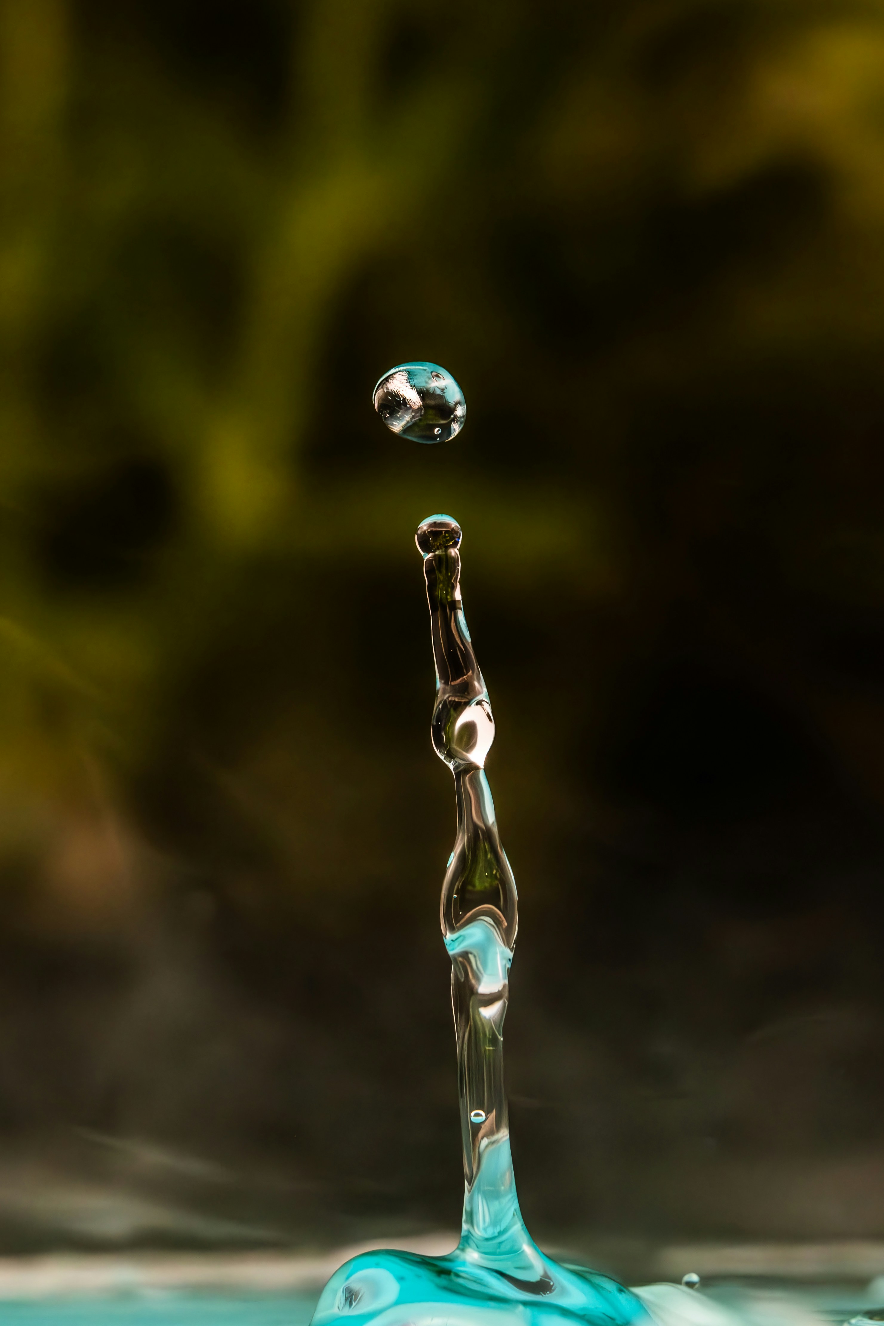 A single water drop falling onto a column of water.