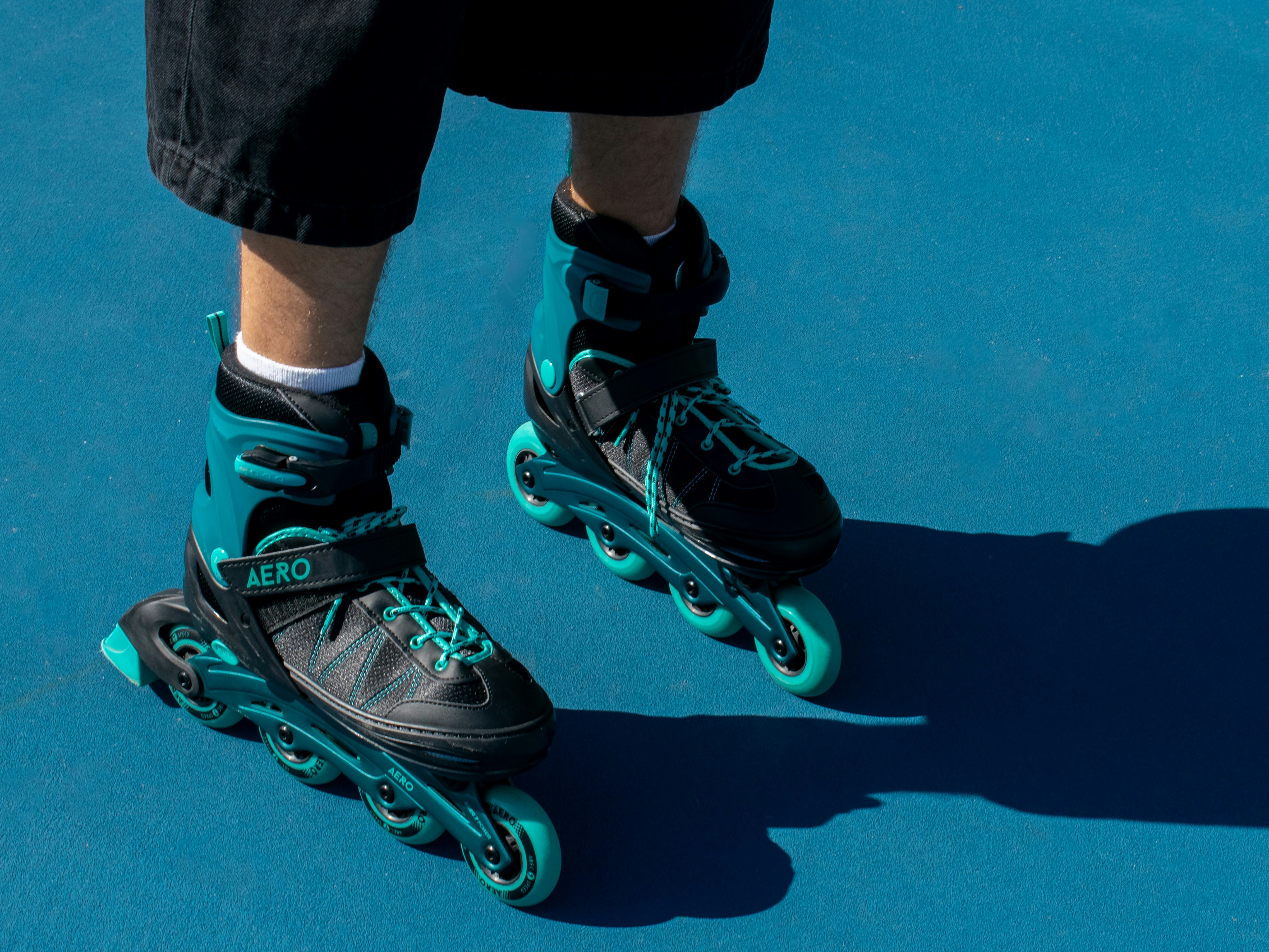 Person wearing teal and black rollerblades on blue surface