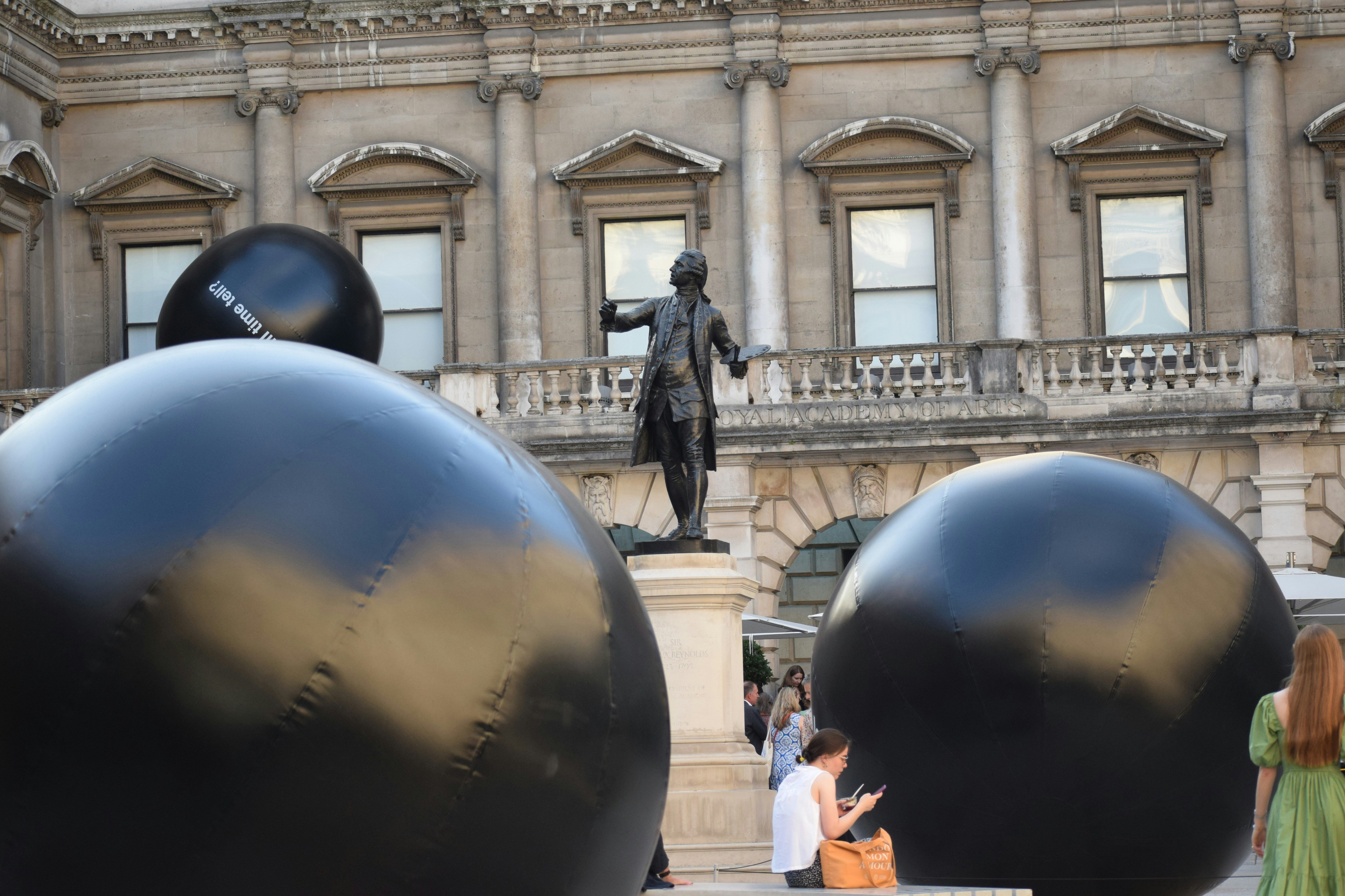 Statue of man between two large black spheres
