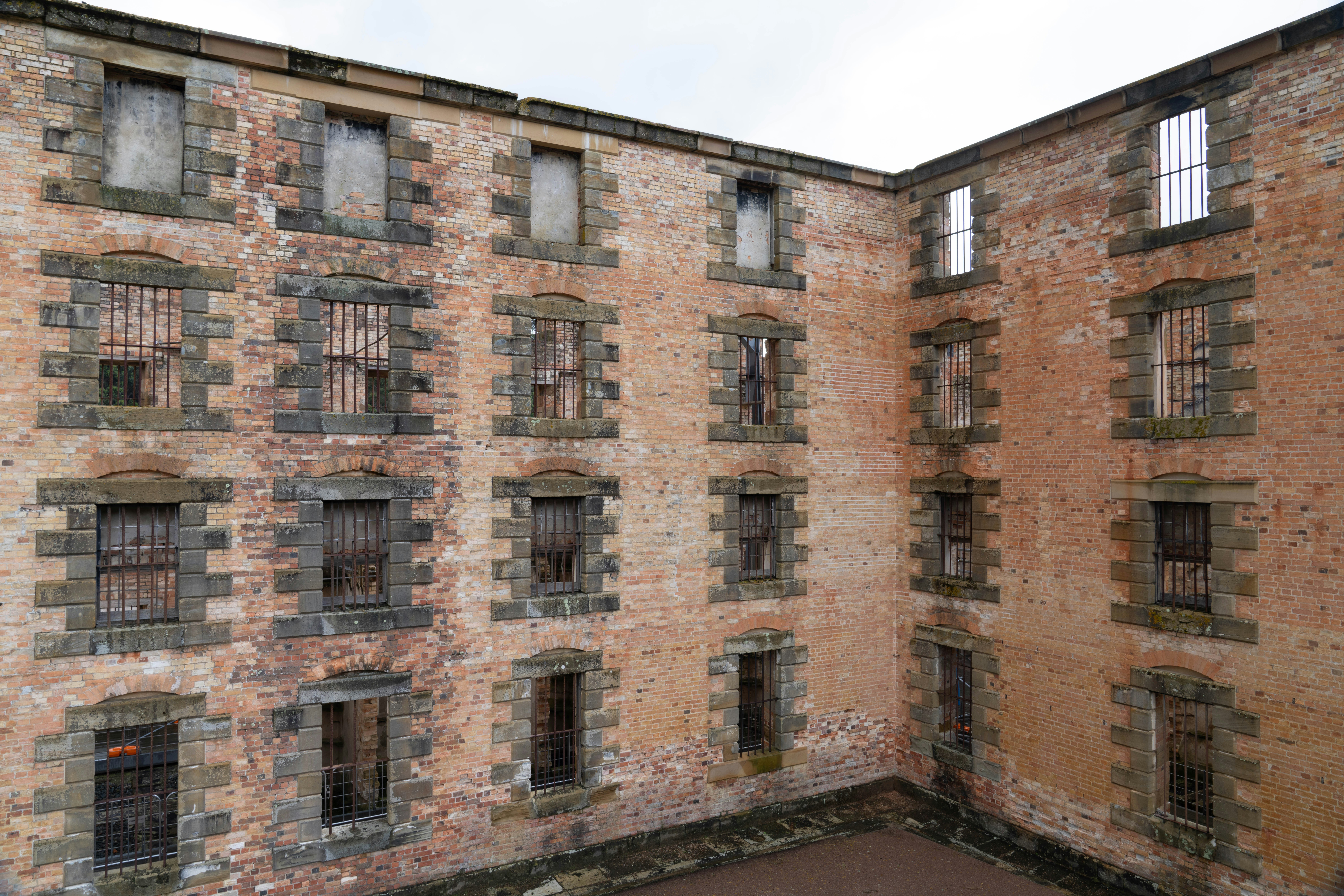 Edificio abandonado de ladrillo con ventanas rotas y aberturas con rejas