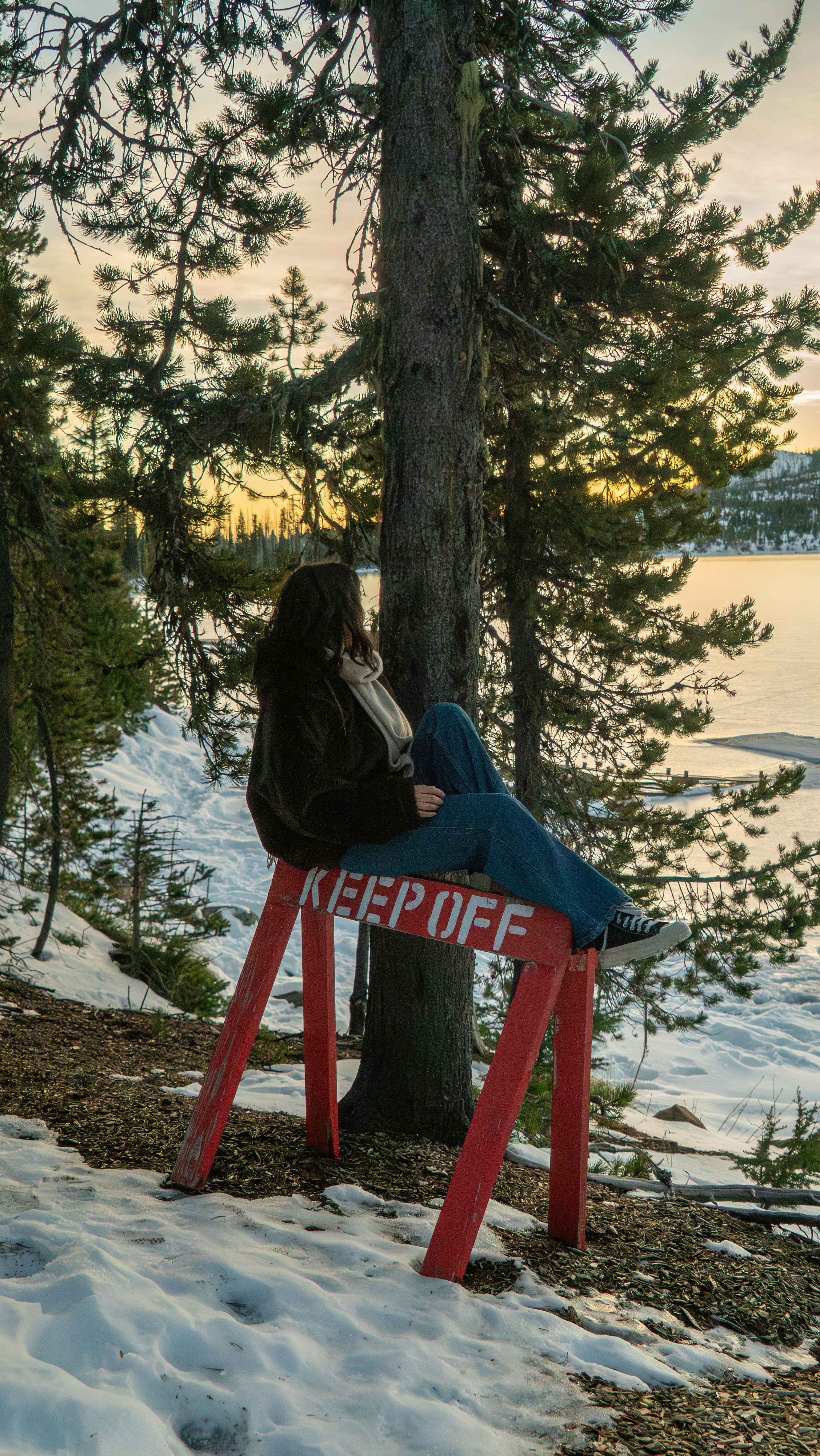 女性が「立ち入り禁止」の標識のある赤いバリケードに座っています。