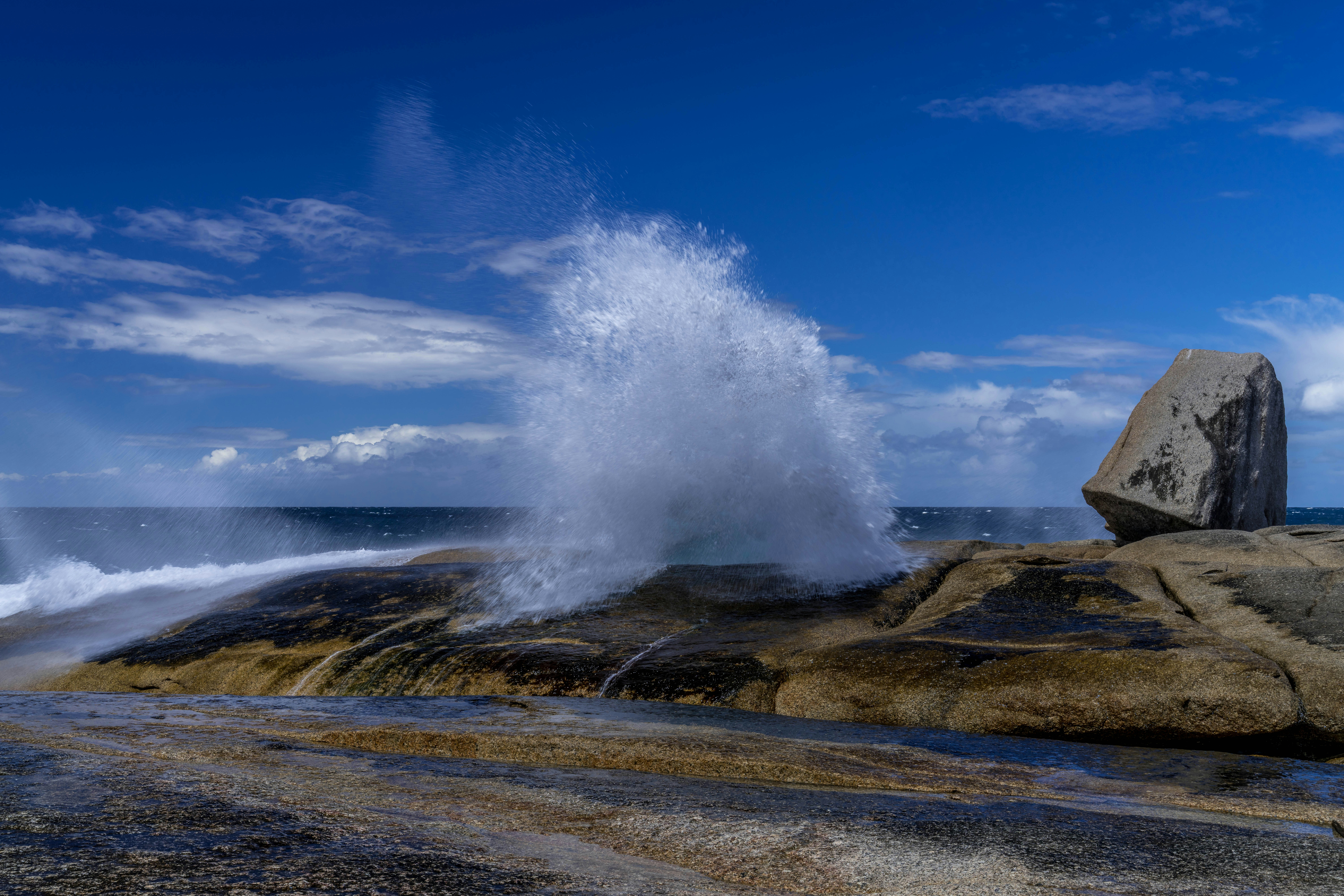 Olas rompiendo contra la costa rocosa bajo un cielo azul
