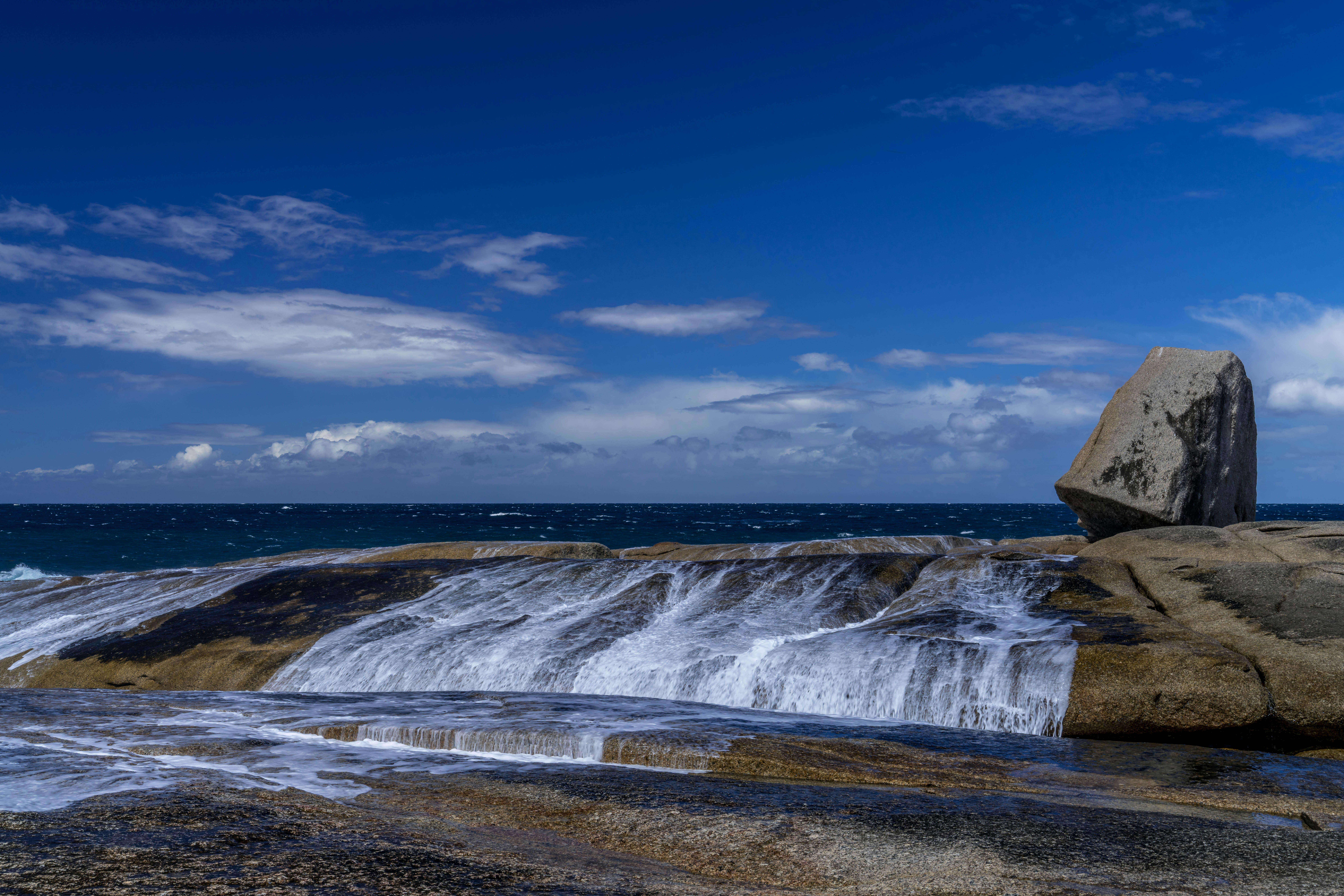 Las olas rompen sobre rocas cerca de una gran roca.