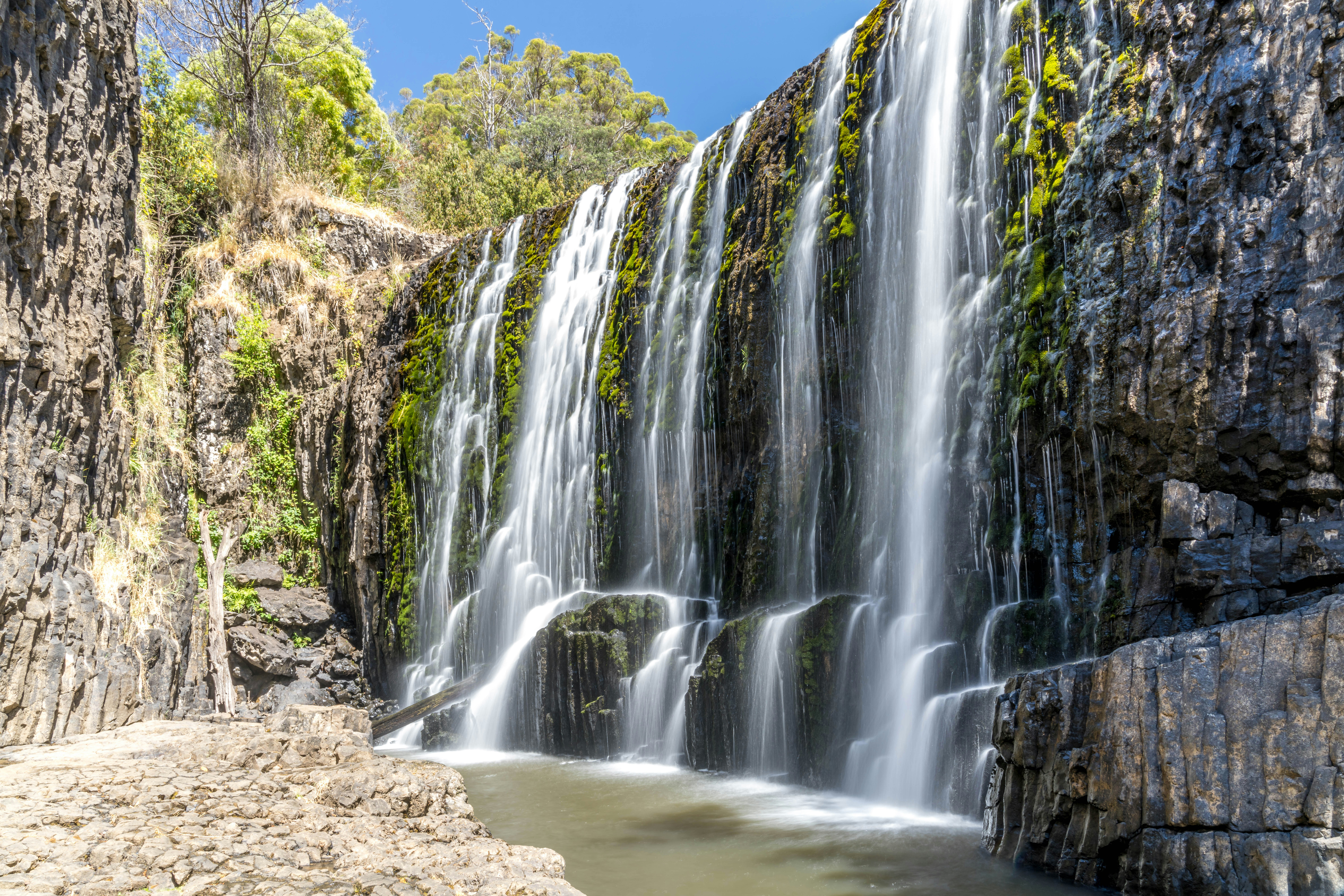Water cascades over mossy rocks into a pool