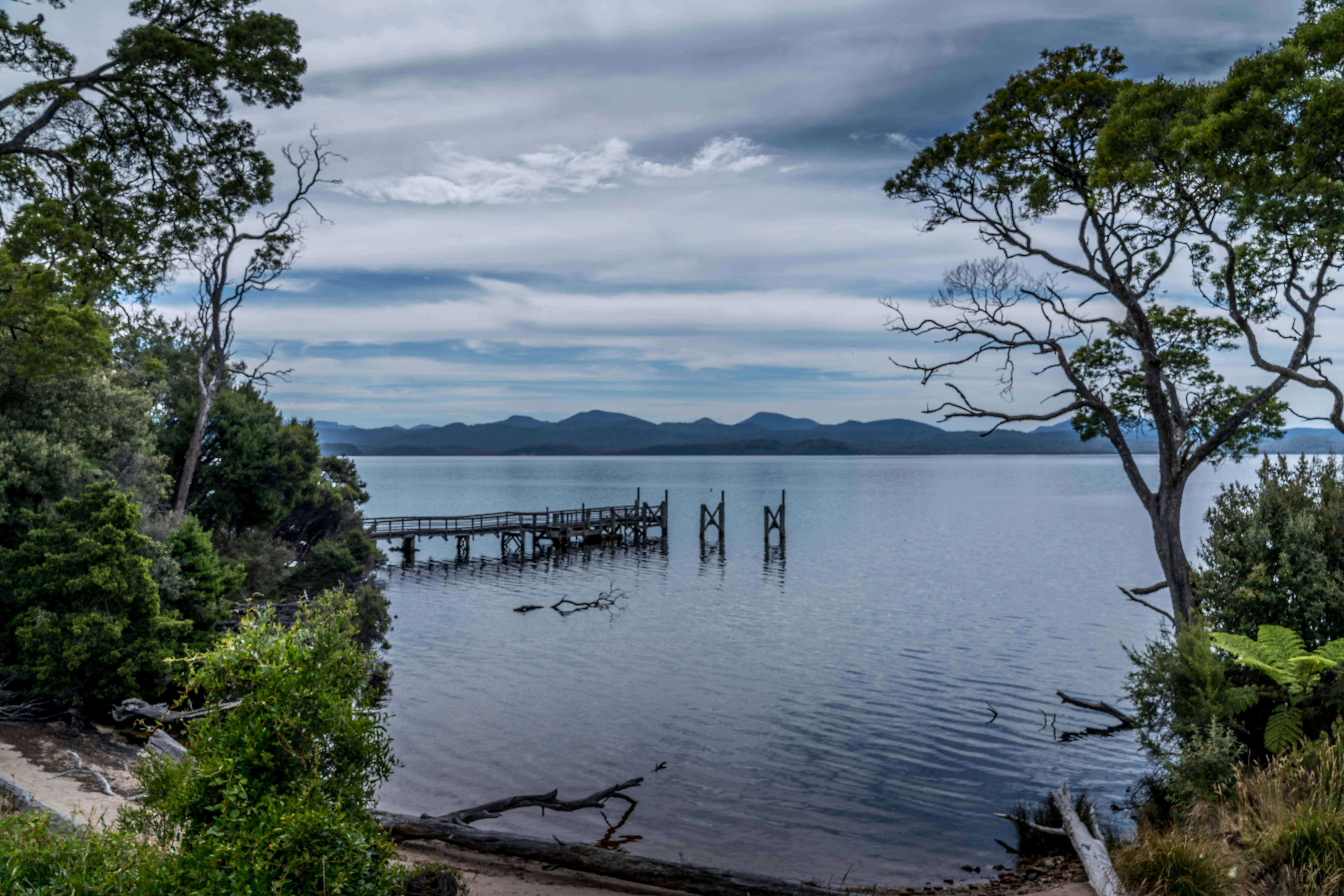 Muelle de madera en un lago tranquilo con montañas lejanas