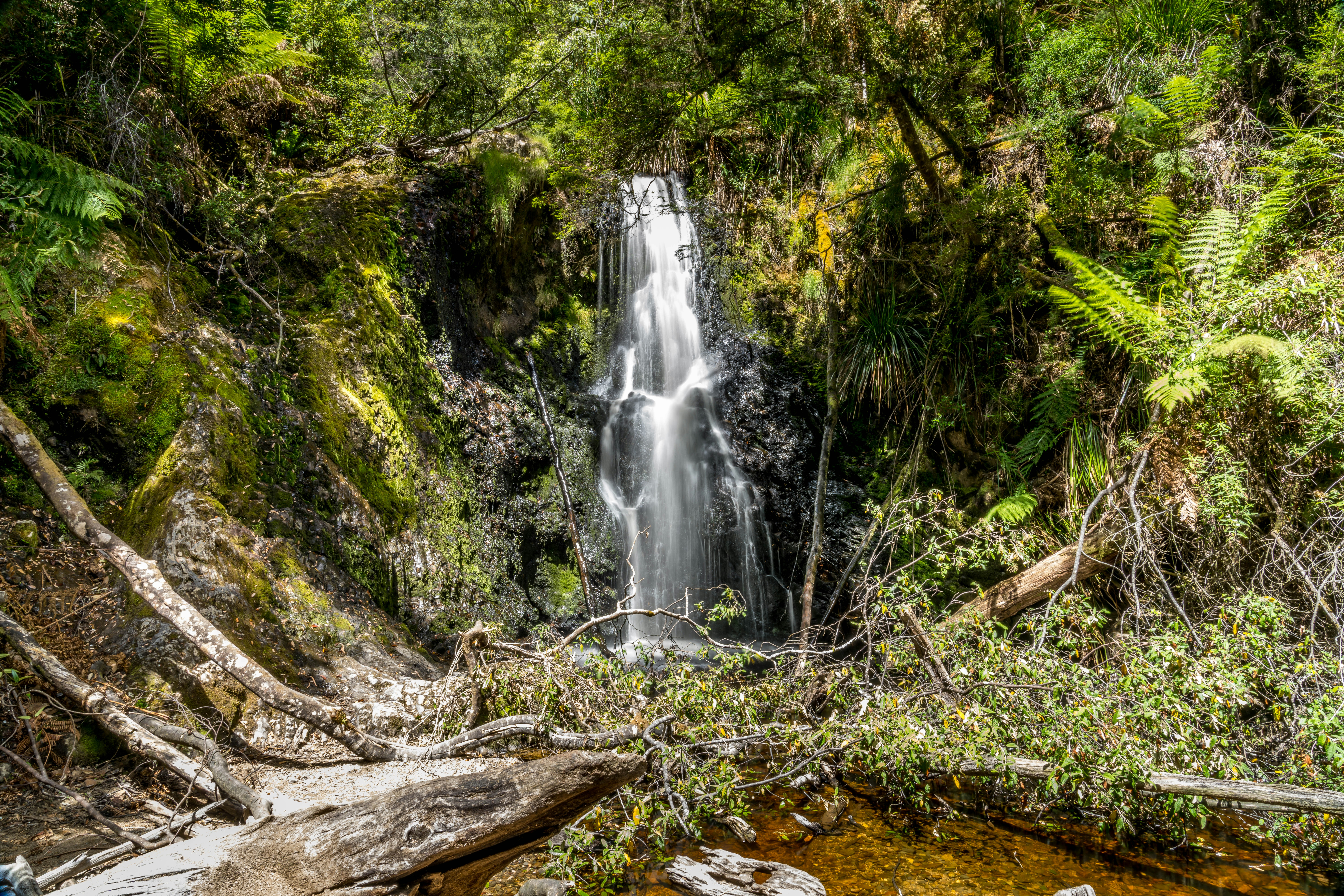 A beautiful waterfall cascades through a lush green forest.
