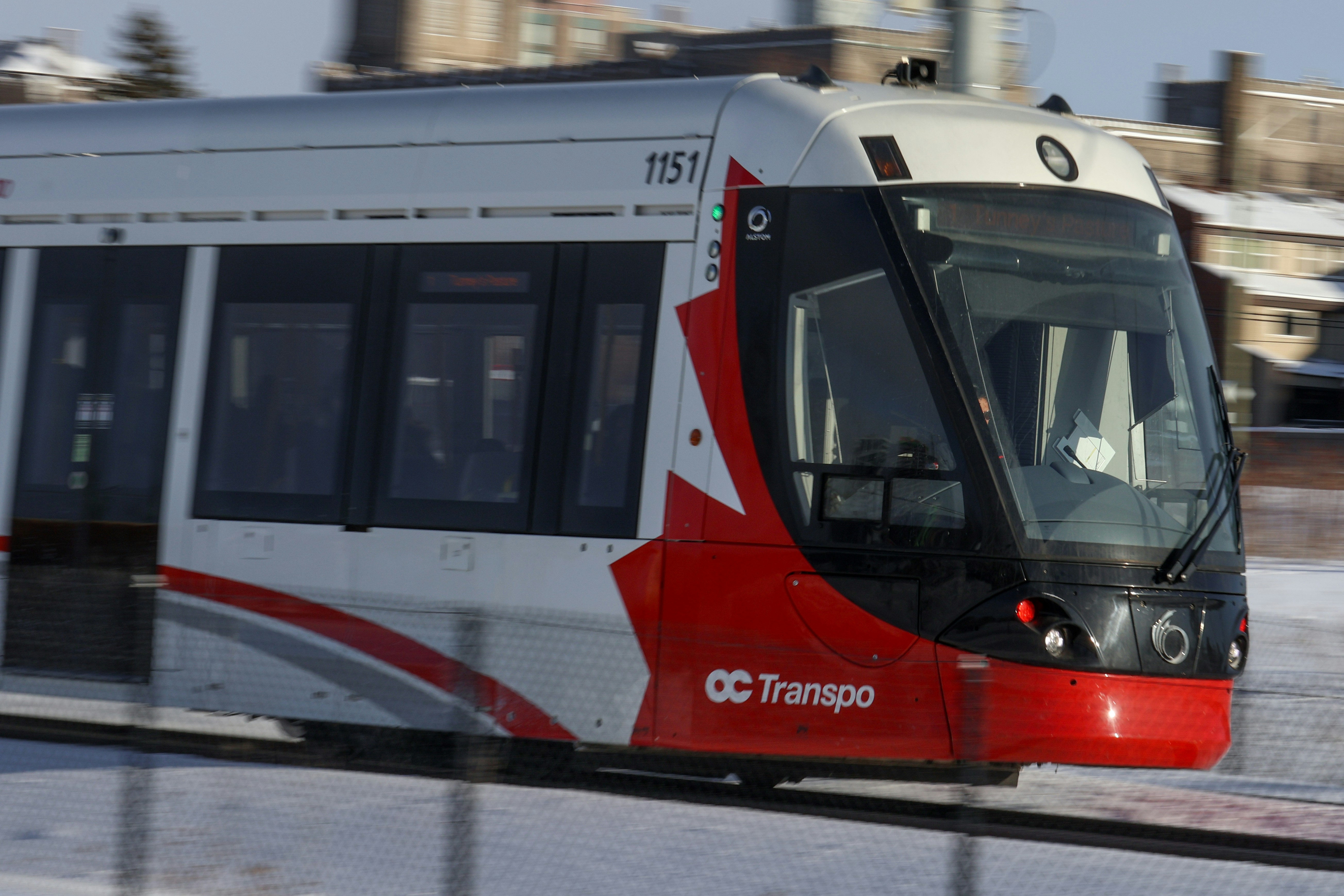 Modern tram with red and white design moving fast.