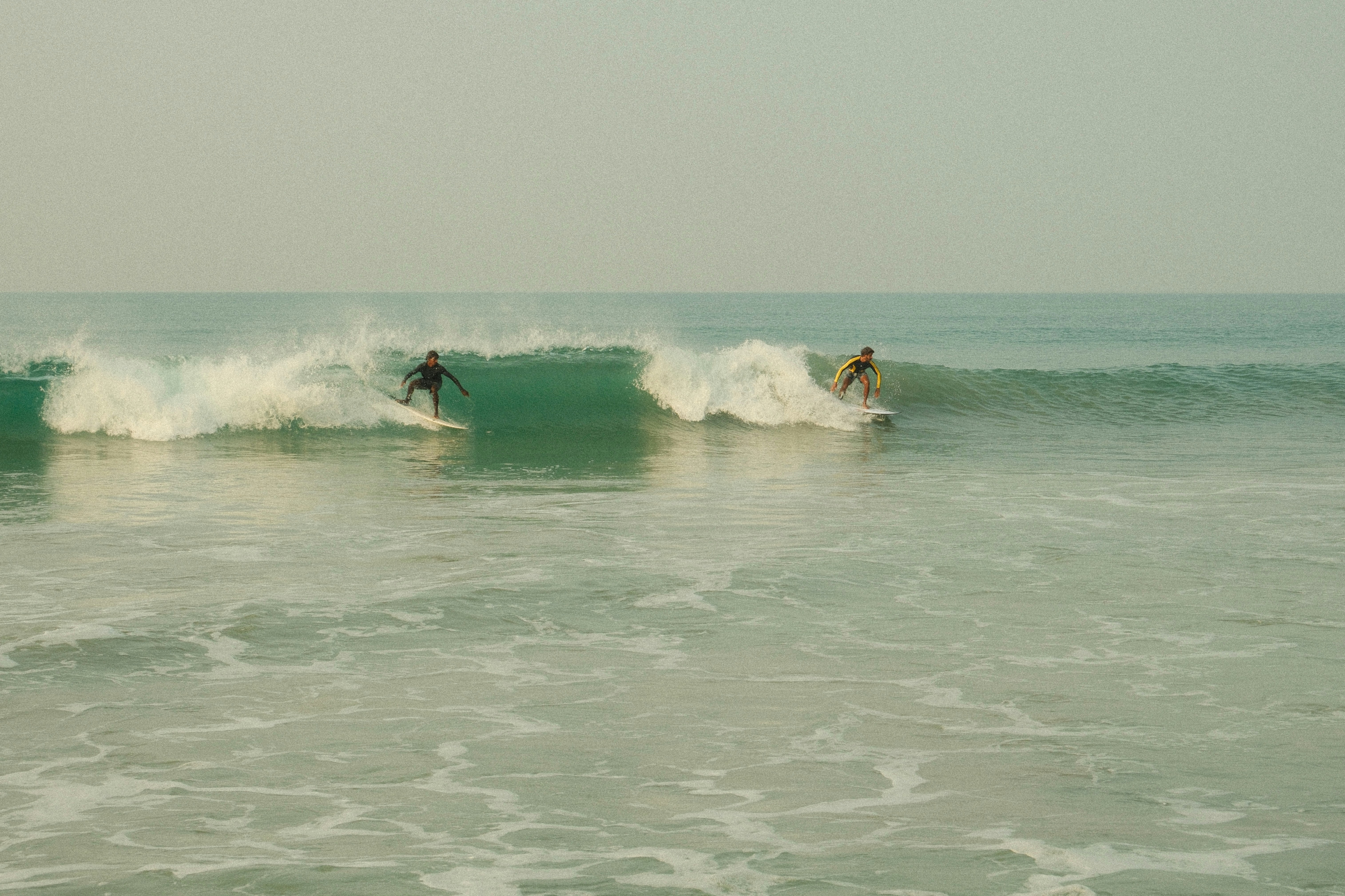 Two surfers riding waves on a clear day