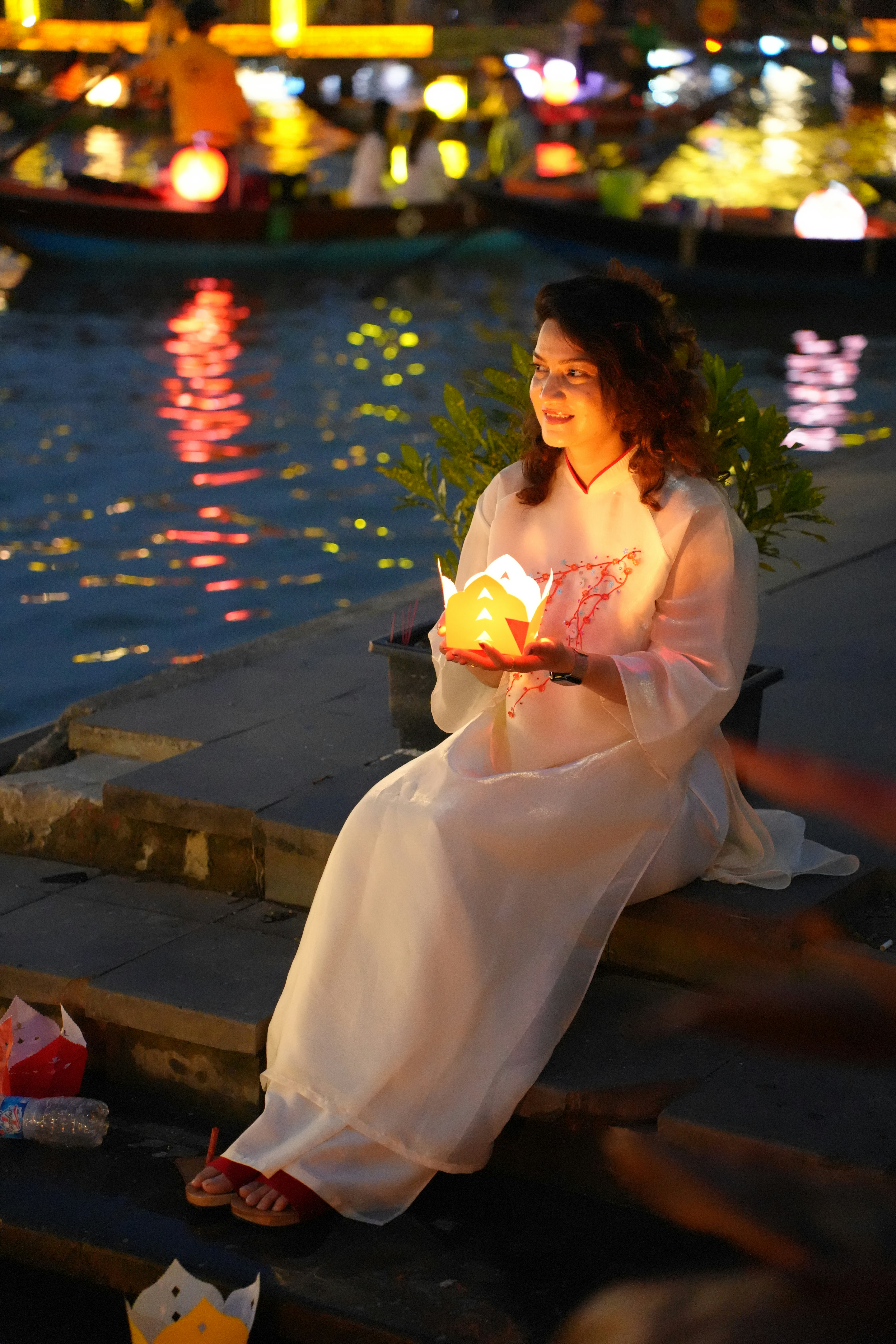 Woman holding a lantern by the water at night