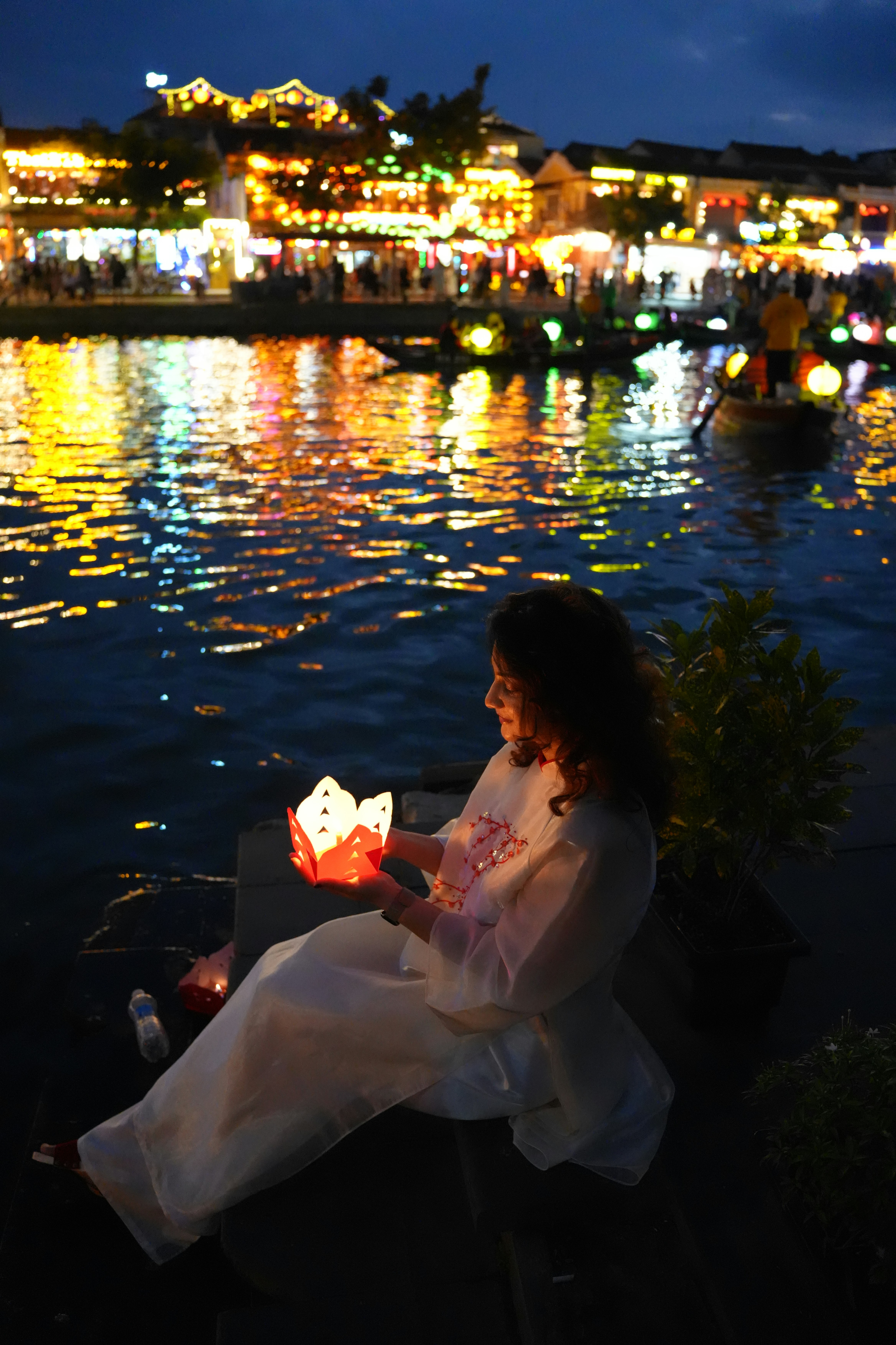 Woman holding a lantern by a river at night
