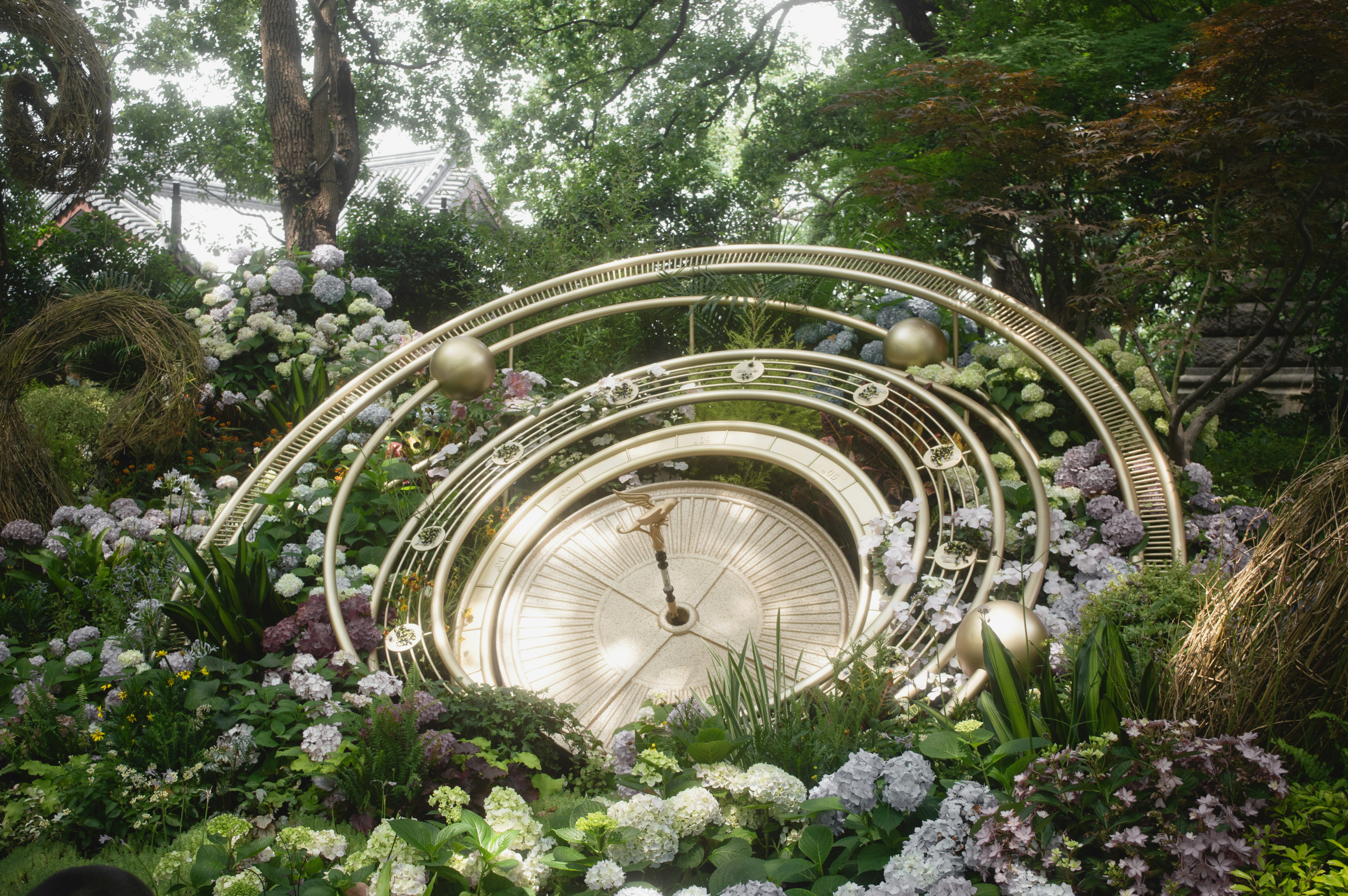 Ornate clock sculpture amidst lush garden foliage
