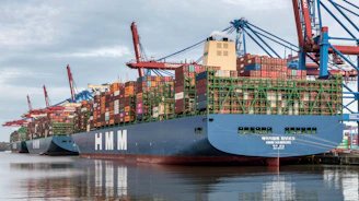Container ships docked at a busy port with cranes.