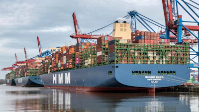 Container ships docked at a busy port with cranes.