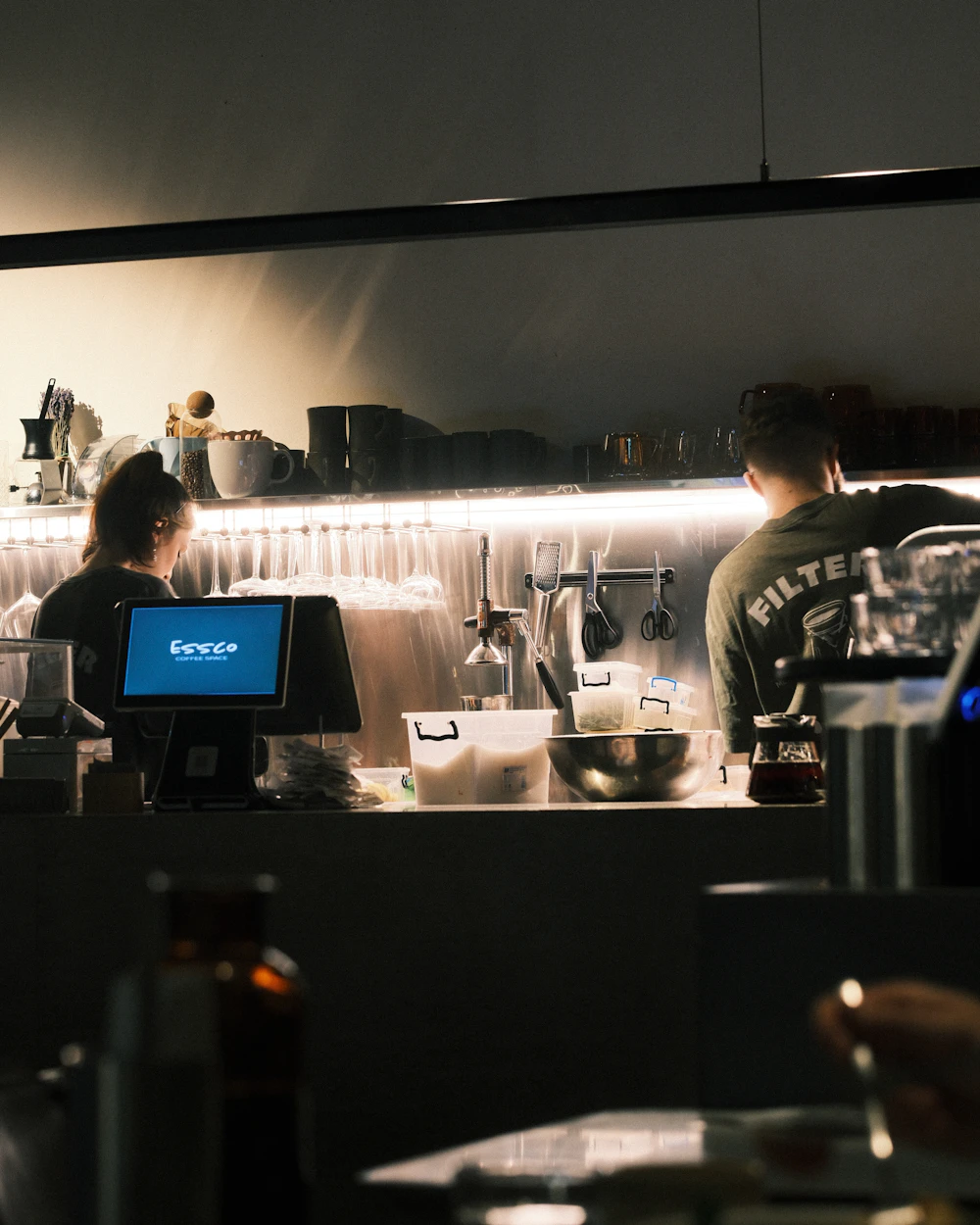 Two hospitality staff working together behind a busy café counter