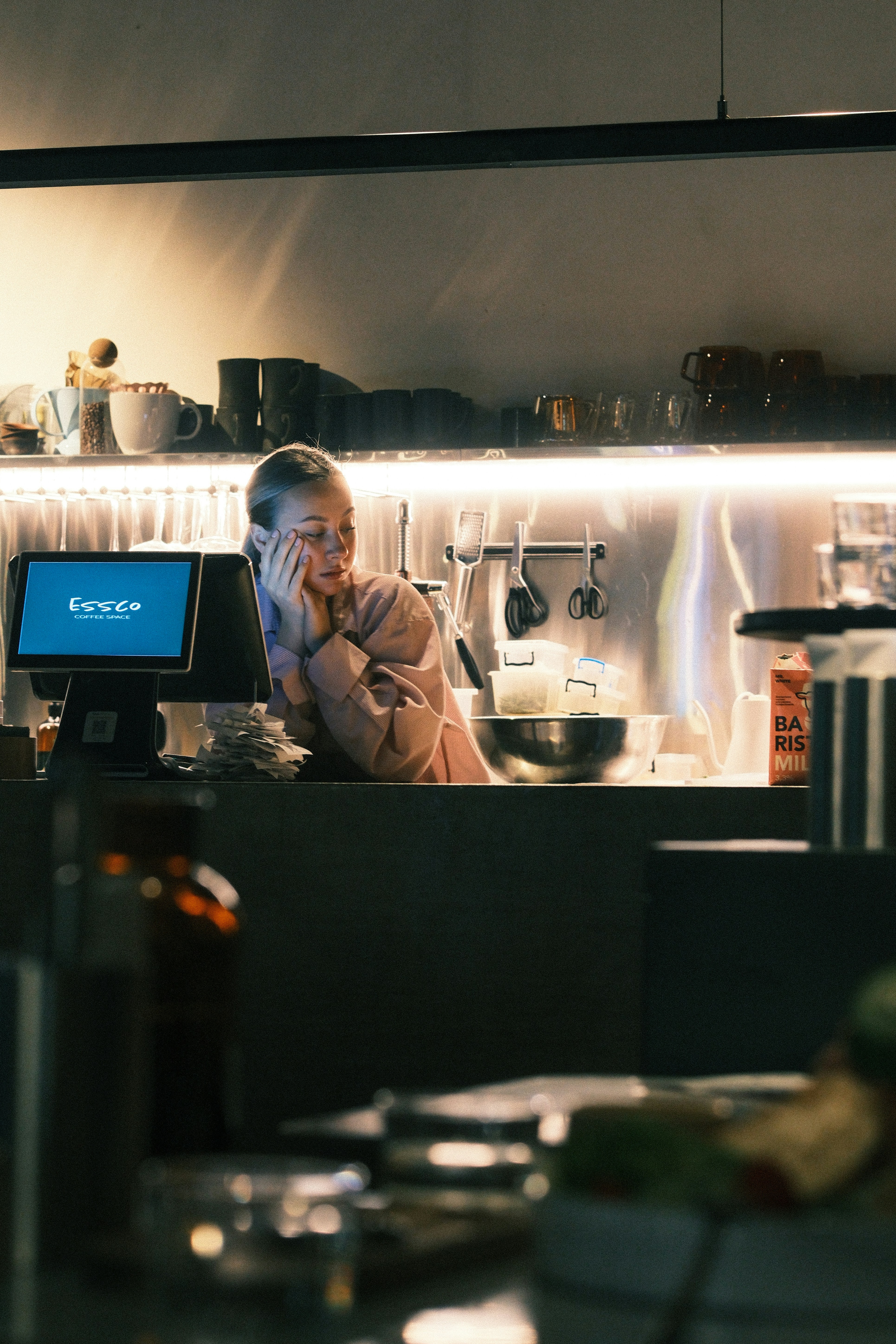 Woman resting head on hand behind counter