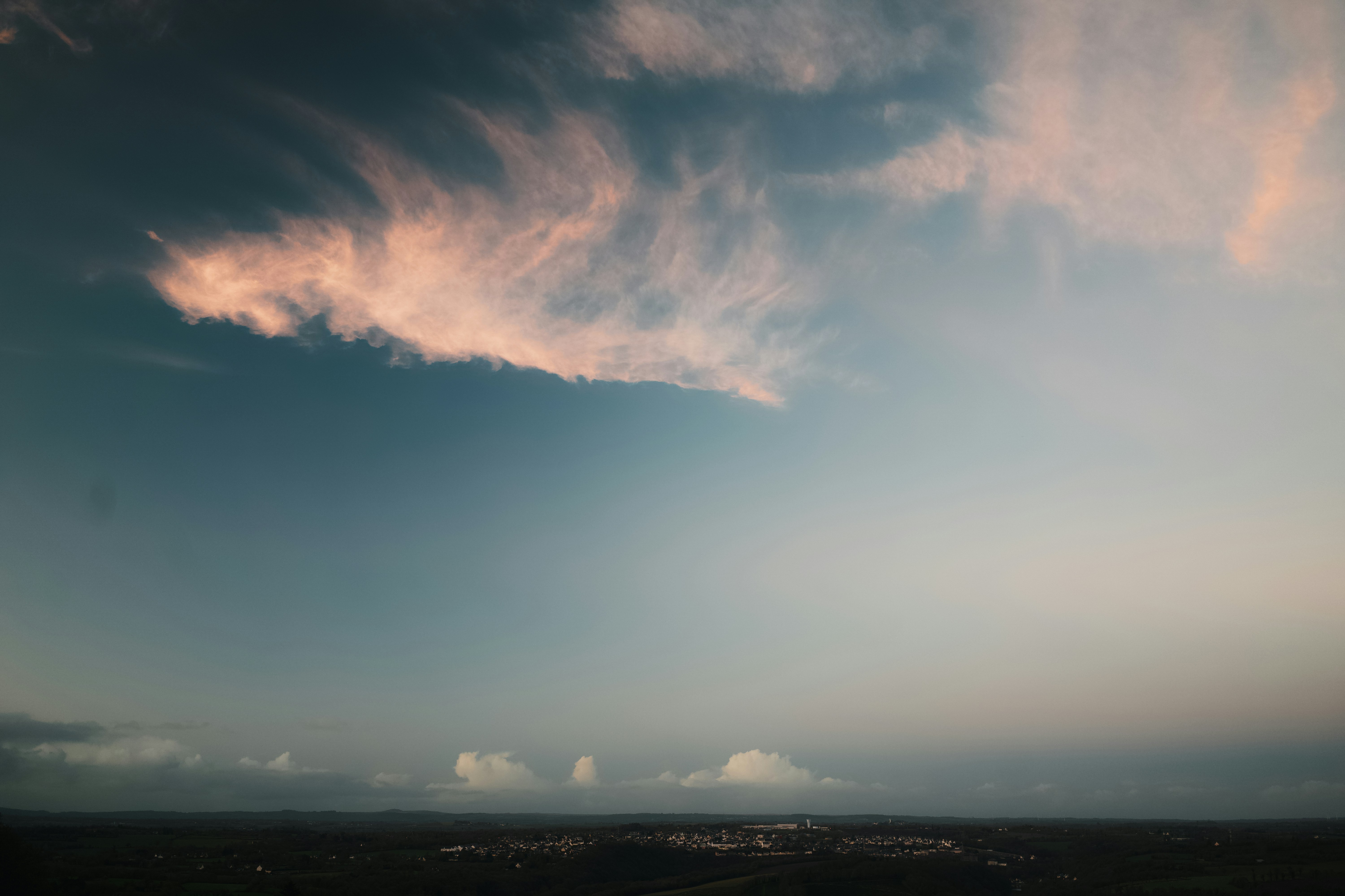 Pink clouds drift across a vast blue sky.
