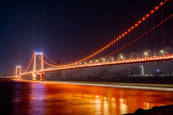 Illuminated suspension bridge over water at night