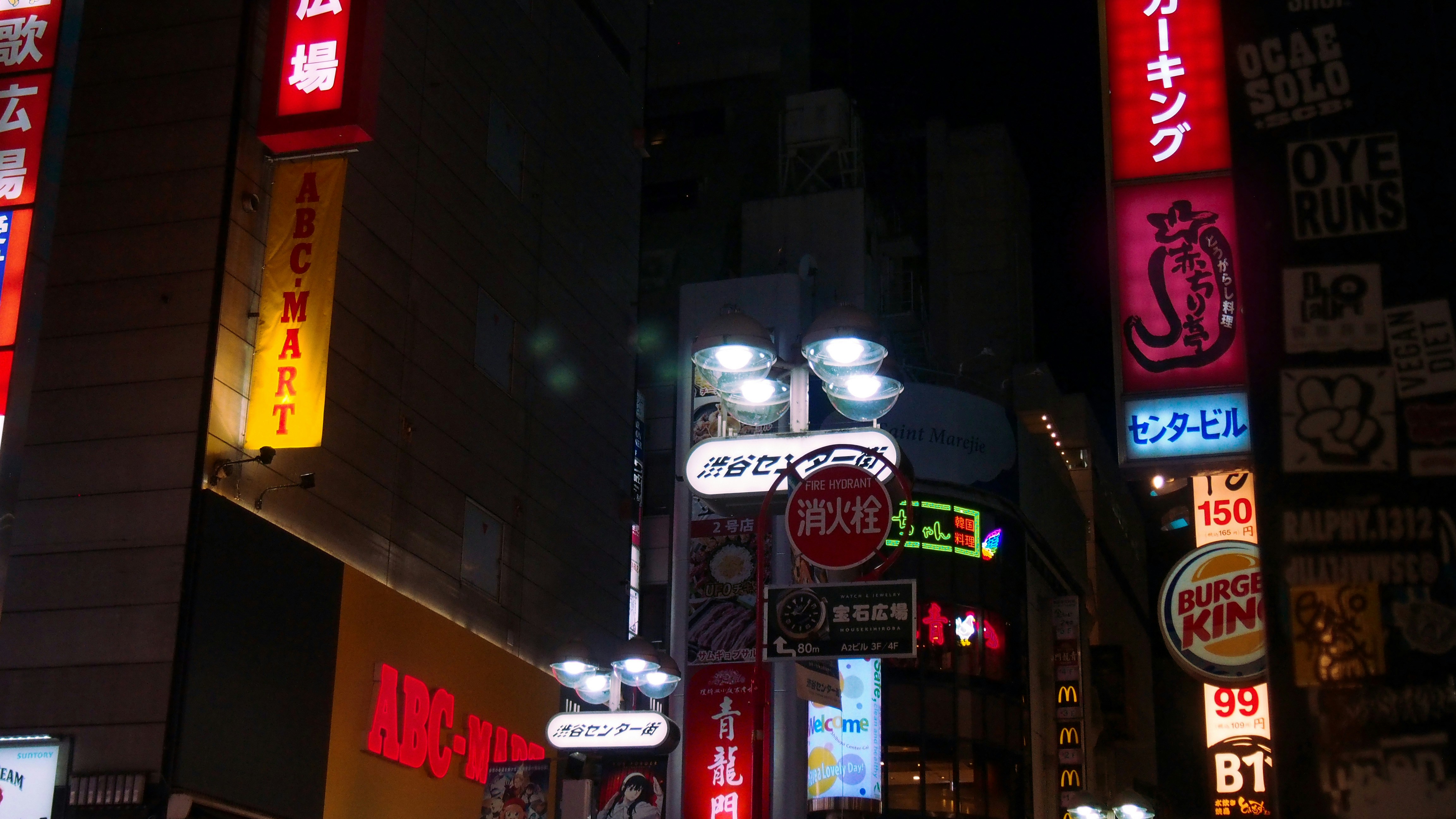 Bright neon signs illuminate a city street at night.