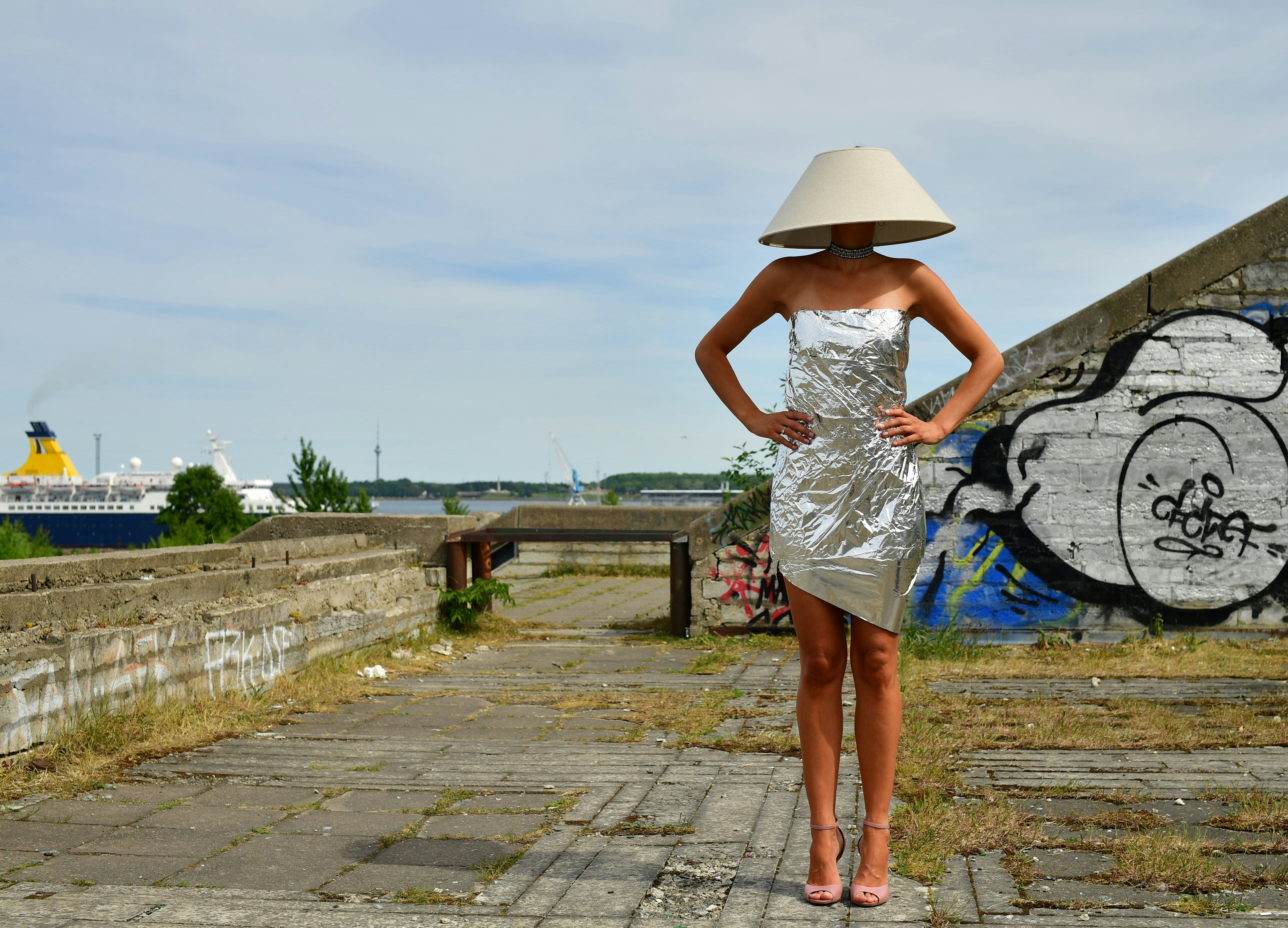 Woman wearing a lampshade and shiny dress outdoors