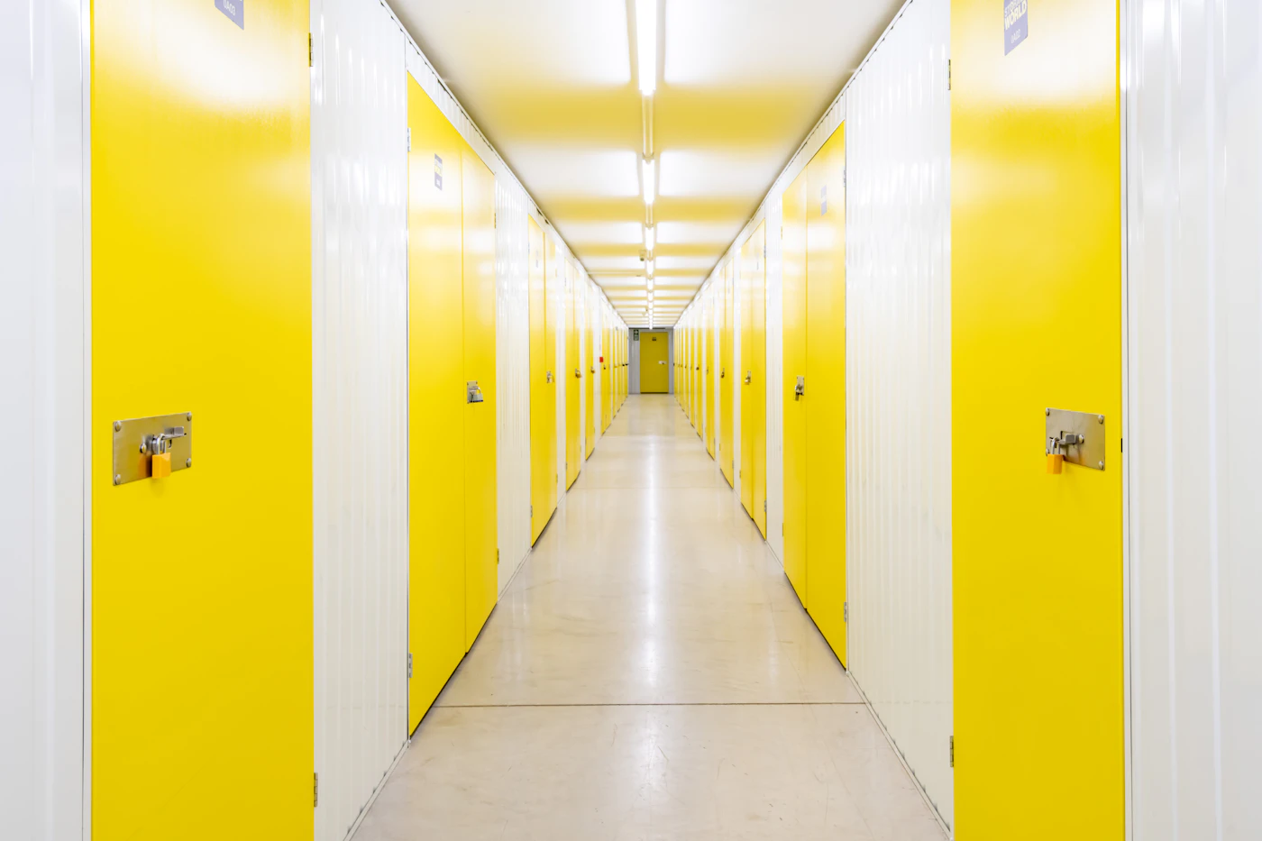 A bright storage corridor lined with yellow unit doors