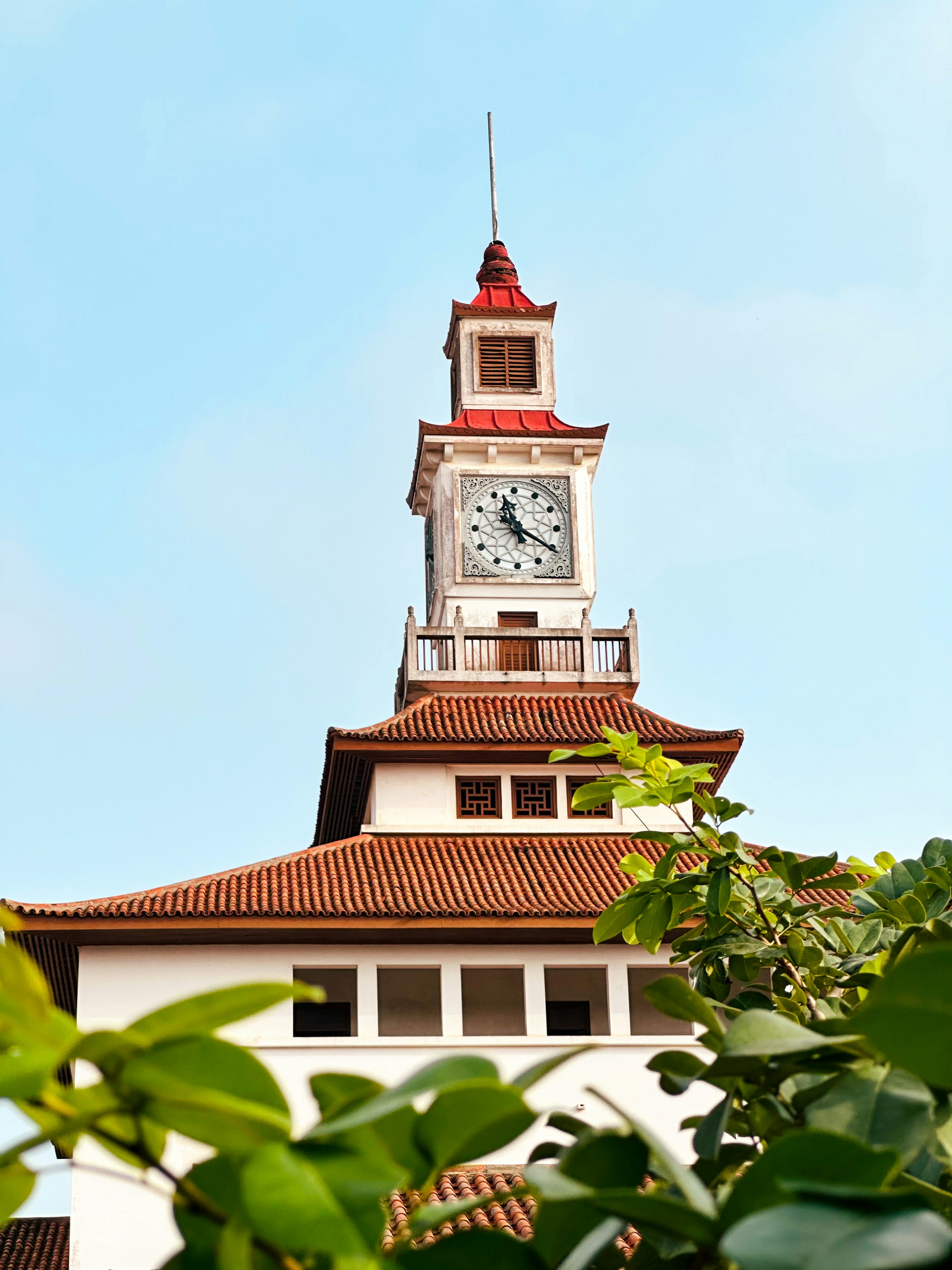 Une tour d’horloge au toit rouge sur un ciel bleu