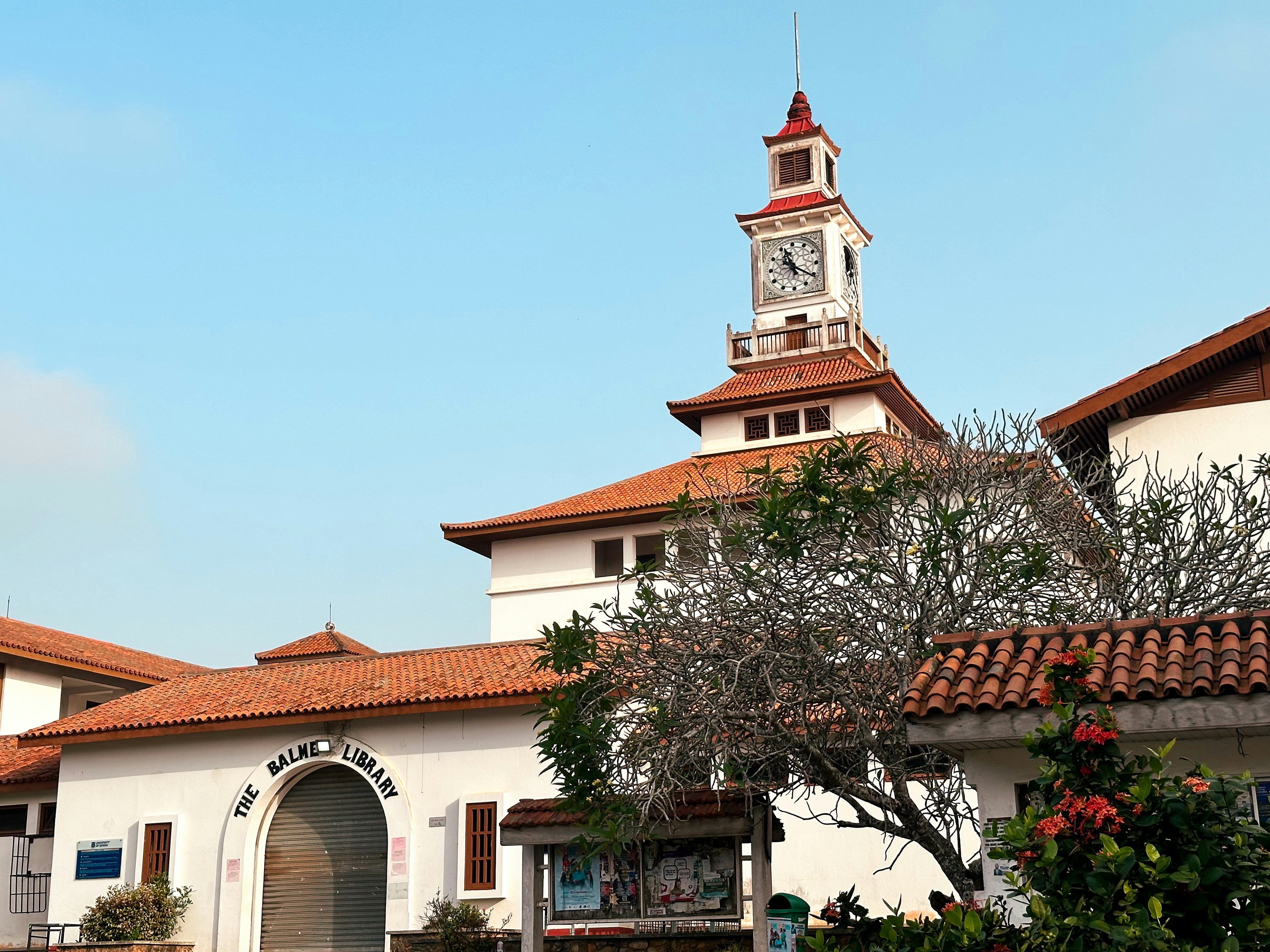 Bâtiment blanc avec une tour d’horloge et un toit en tuiles.