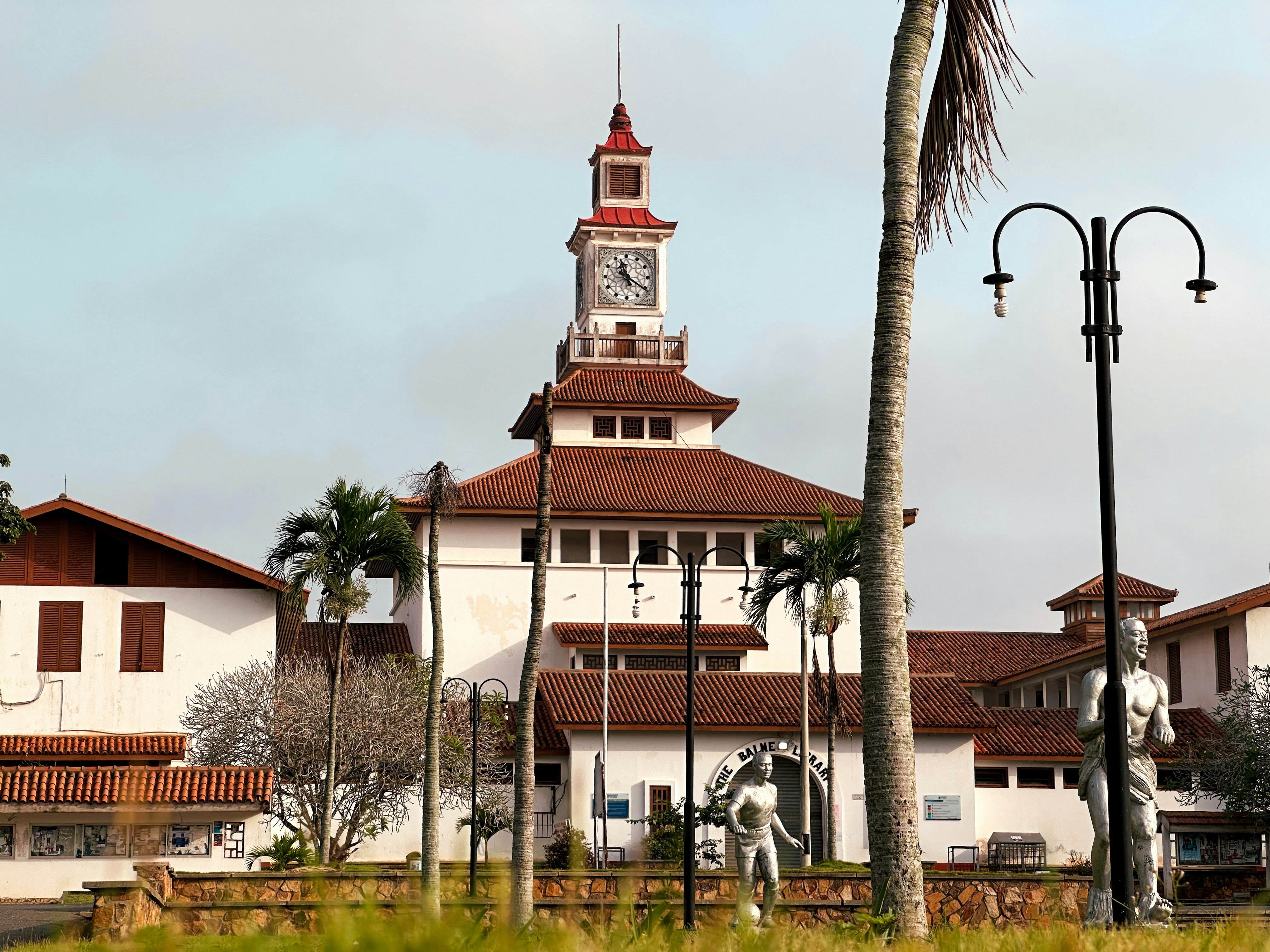 Bâtiment blanc avec une tour d’horloge et des palmiers.