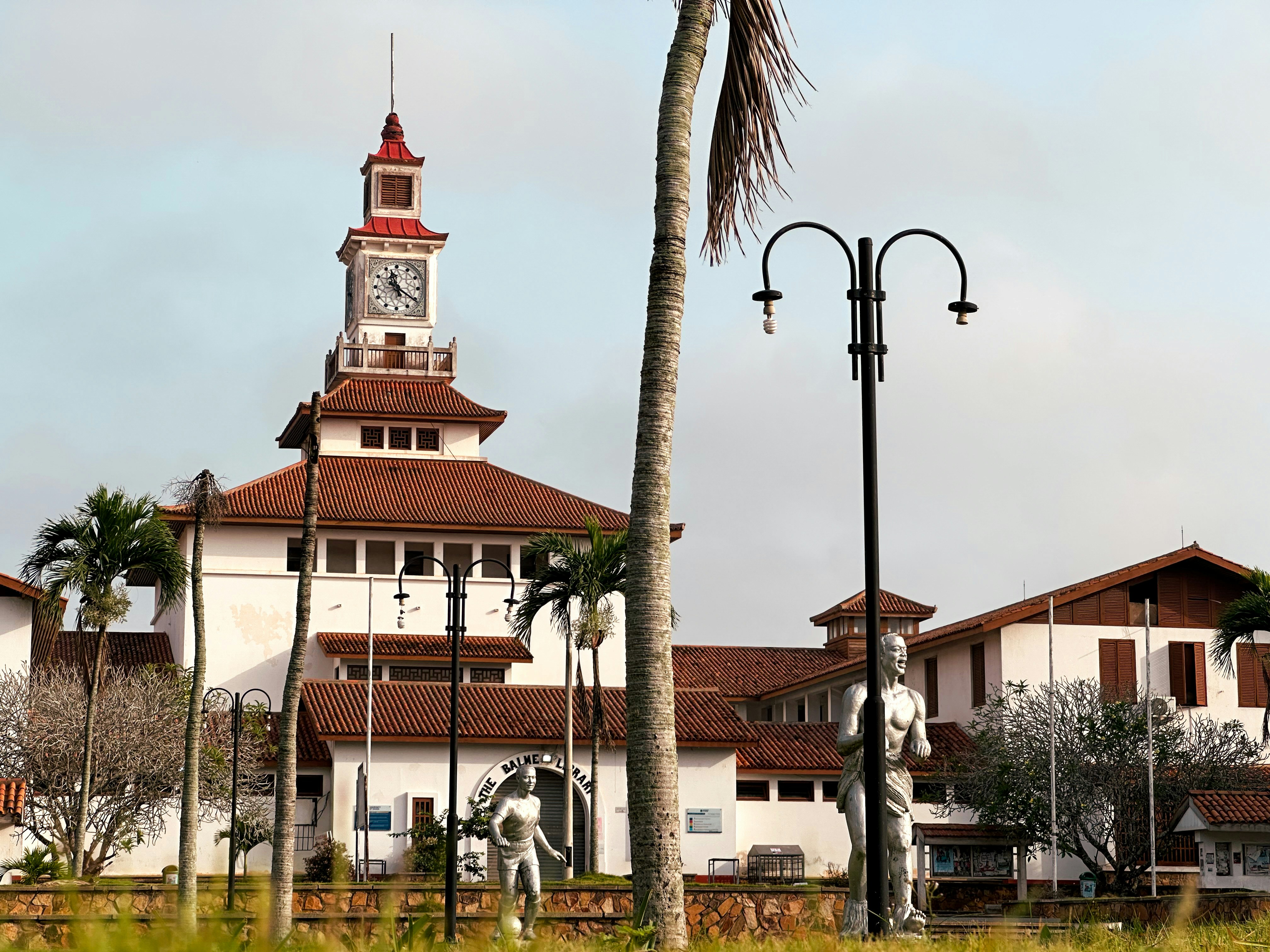 Bâtiment blanc avec tour d’horloge et palmiers