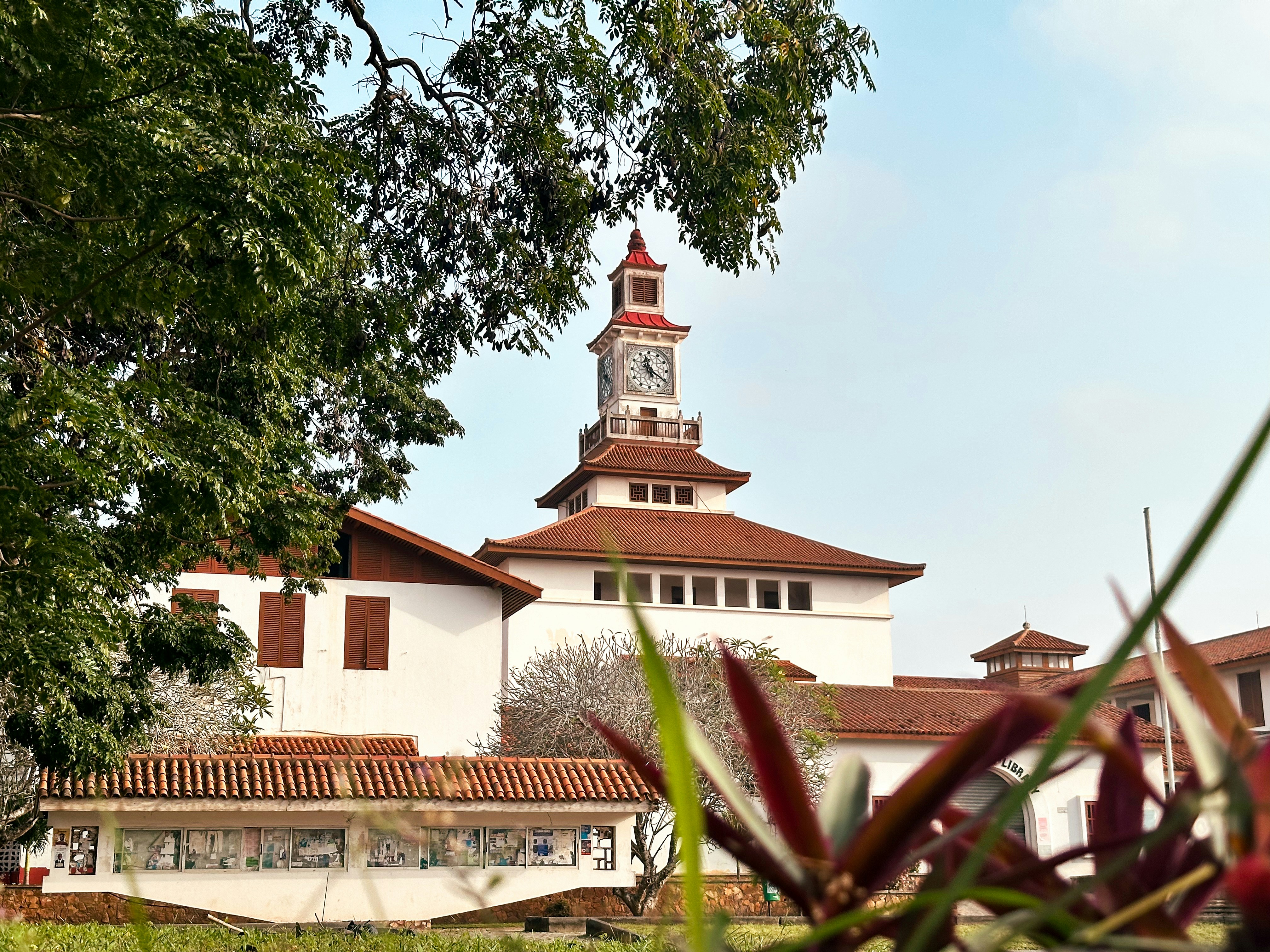 Bâtiment blanc avec une tour d’horloge et un toit rouge.