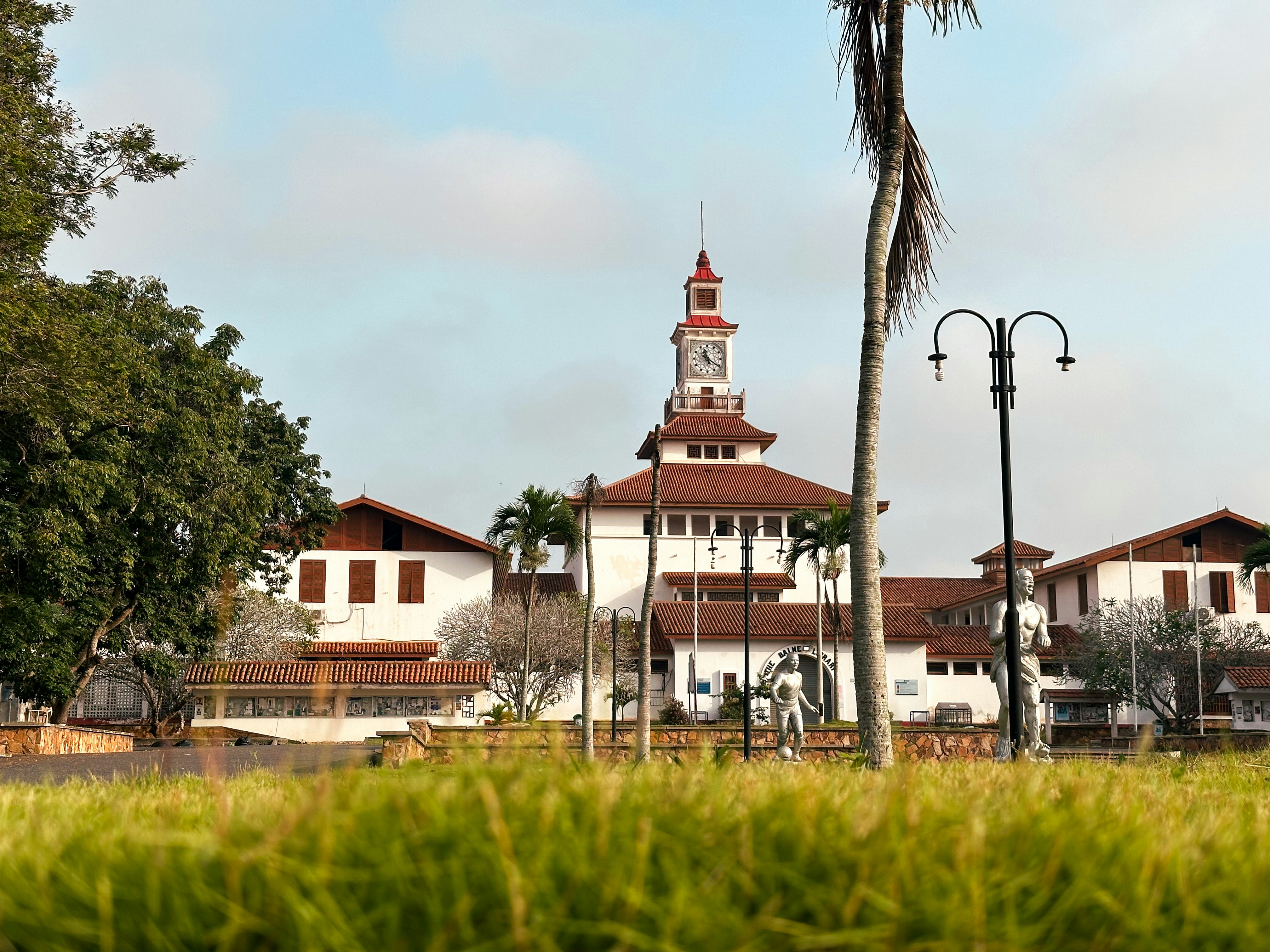 Bâtiment avec une tour d’horloge et des structures blanches environnantes.