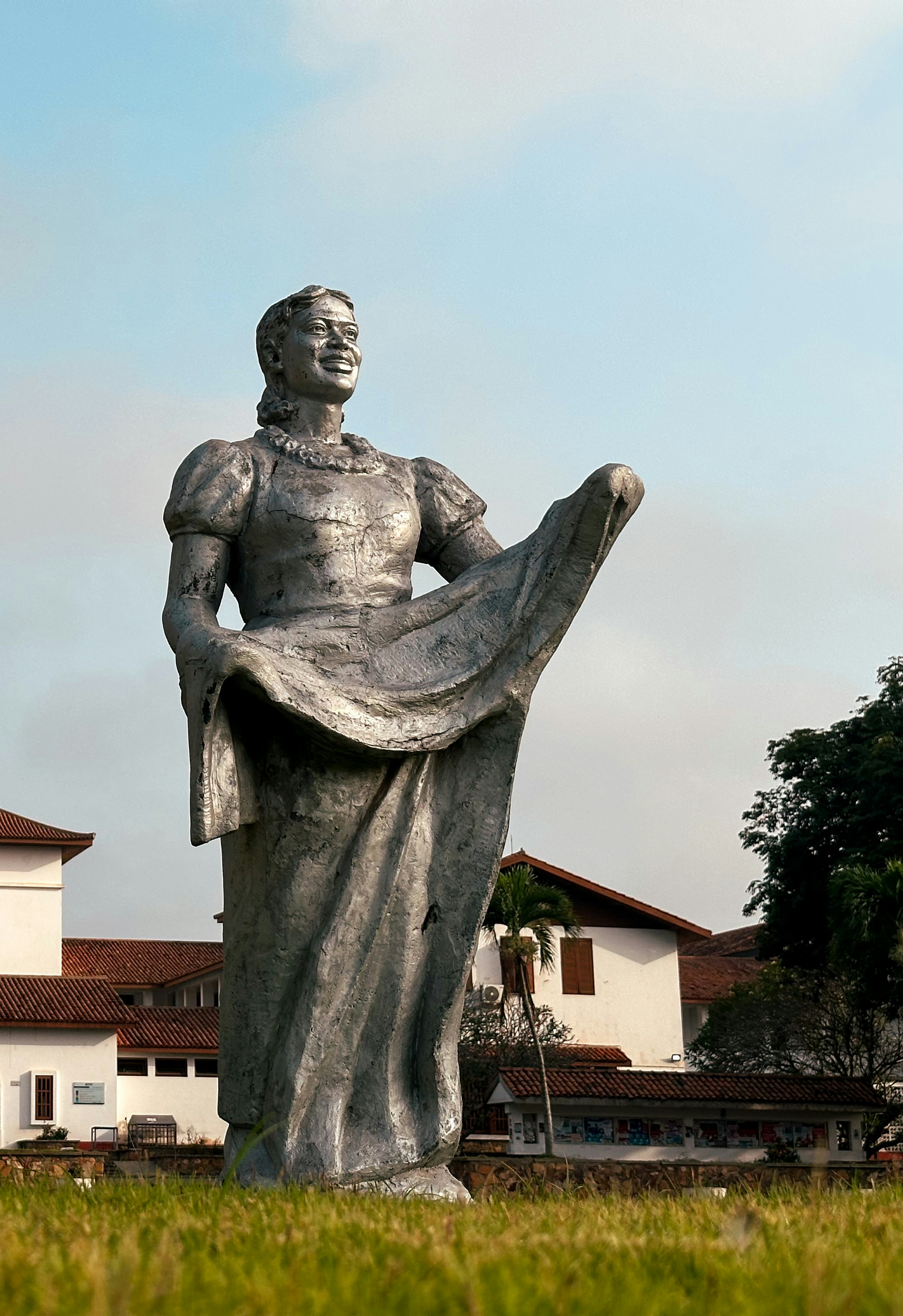 Une grande statue métallique d’une femme en robe.