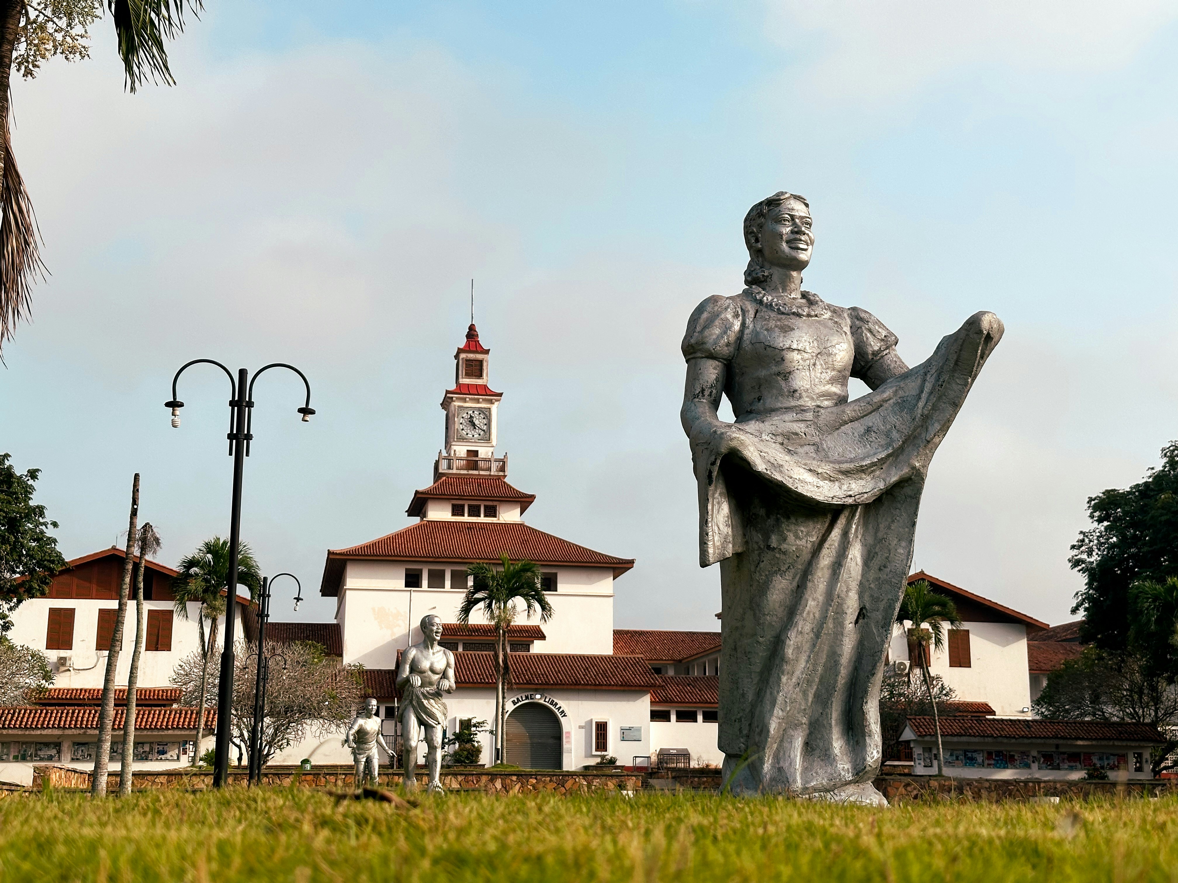 Statue devant un bâtiment historique avec une tour d’horloge.