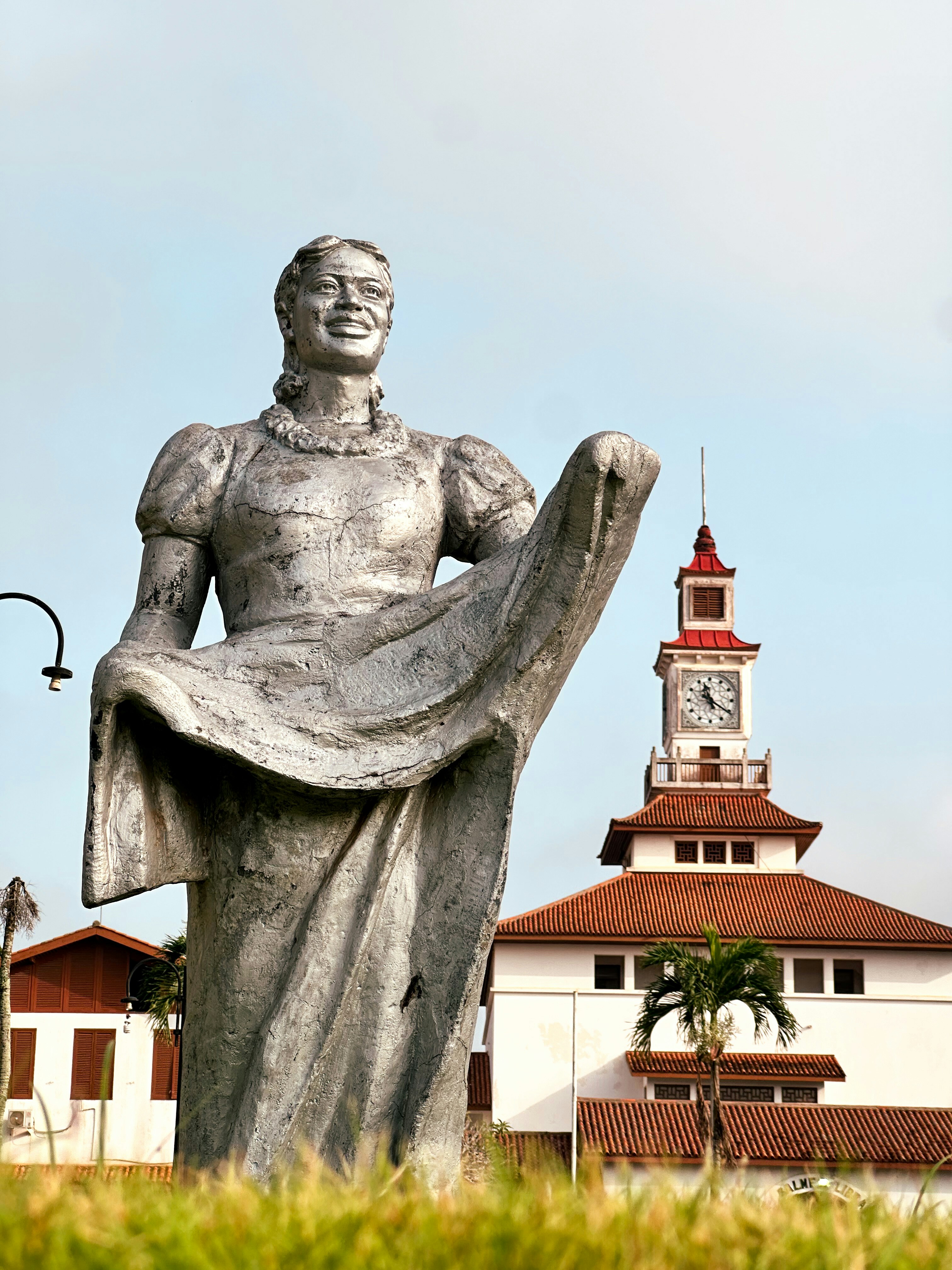 Grande statue d’une femme en tenue avec une tour d’horloge