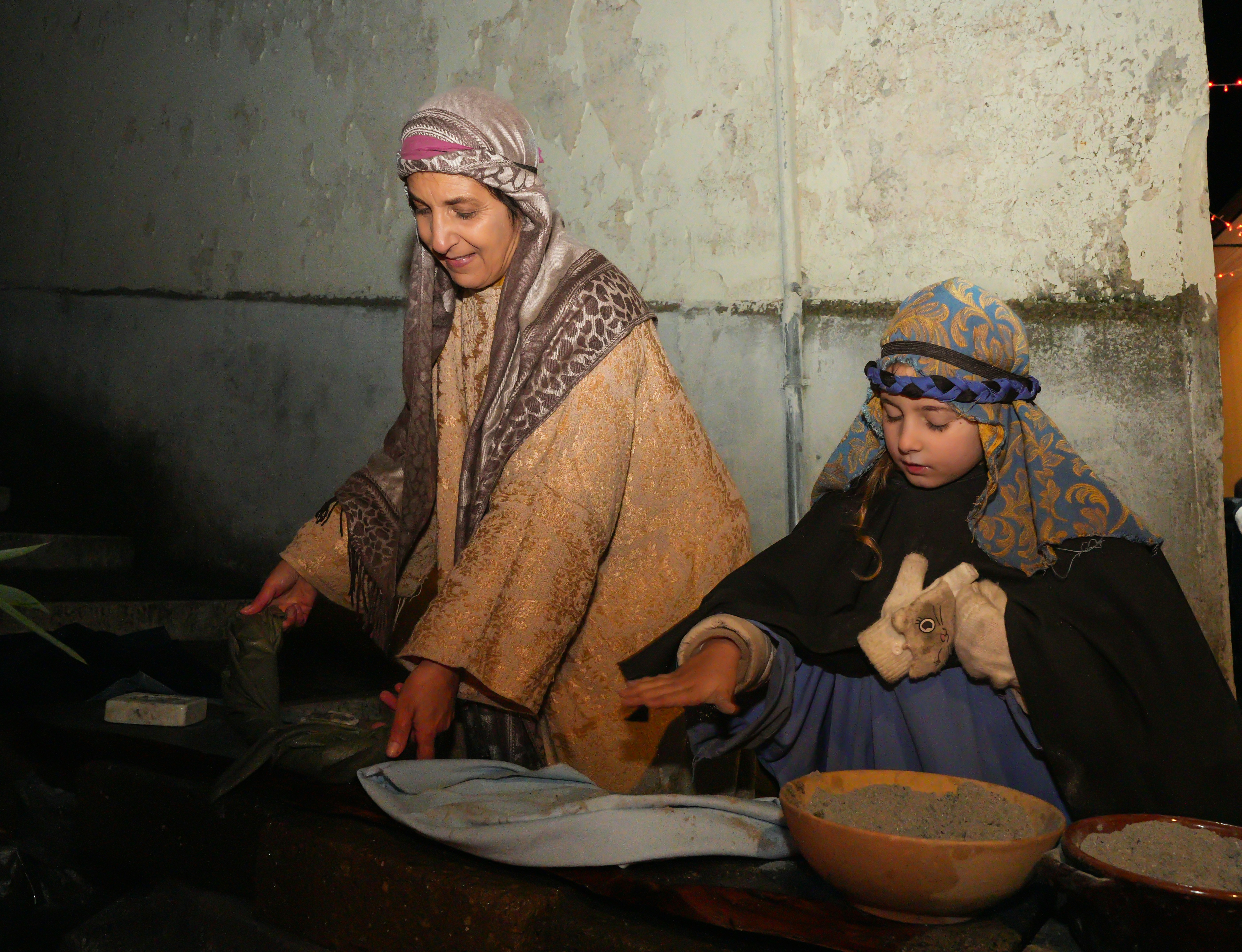 Two women dressed in historical clothing working together.