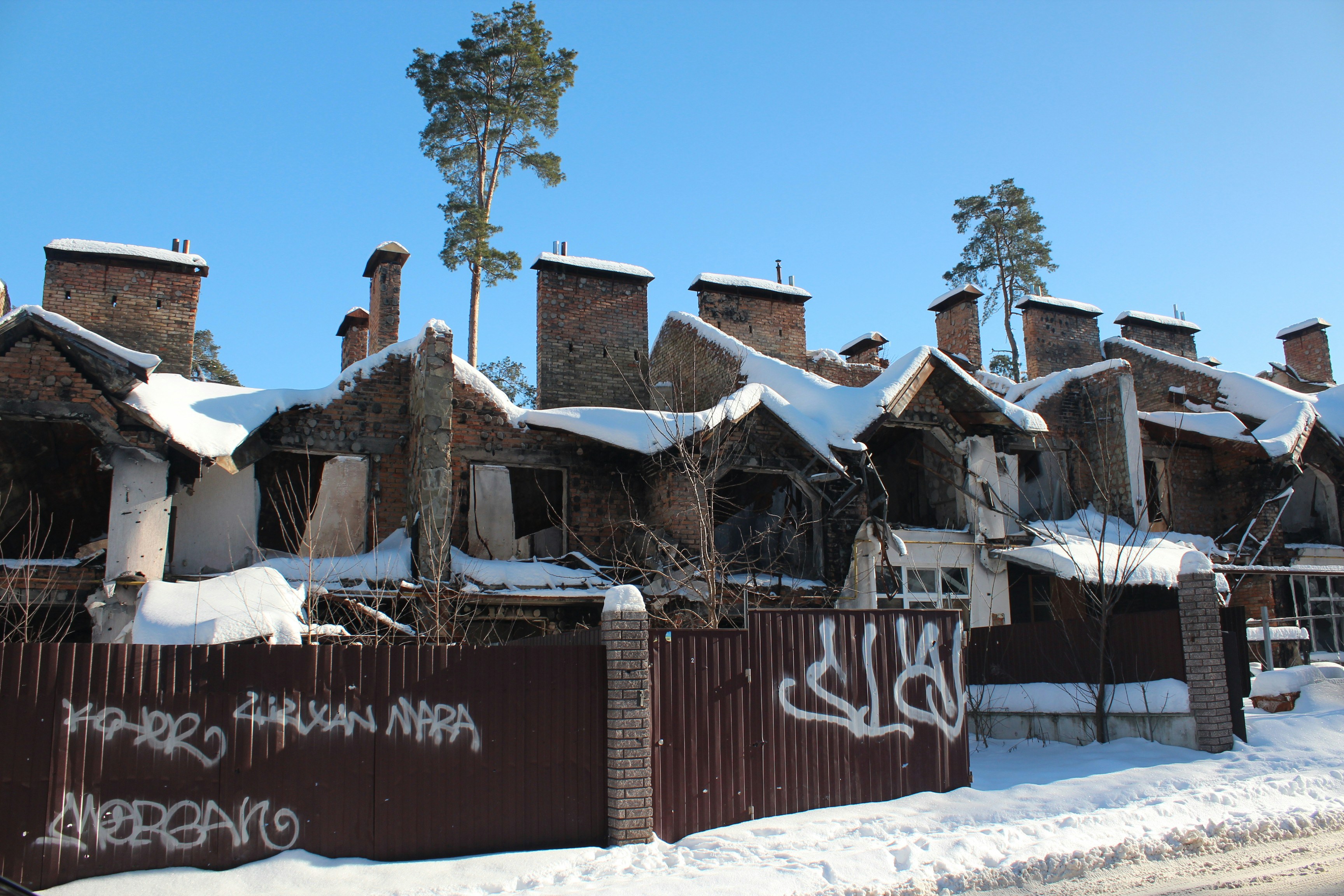 Snow-covered brick townhouses with graffiti on fence