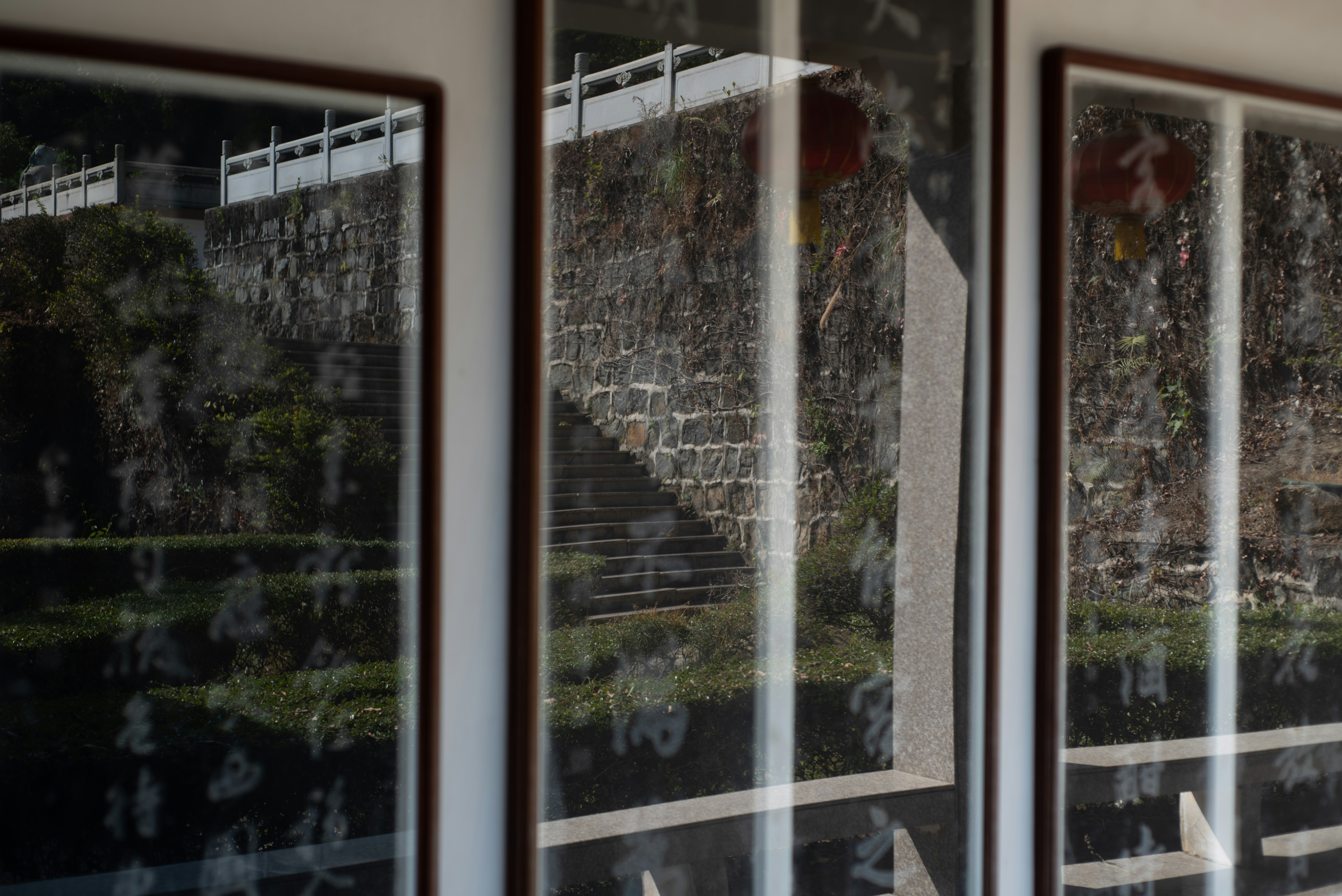 Three framed artworks with reflections of stairs and stone wall