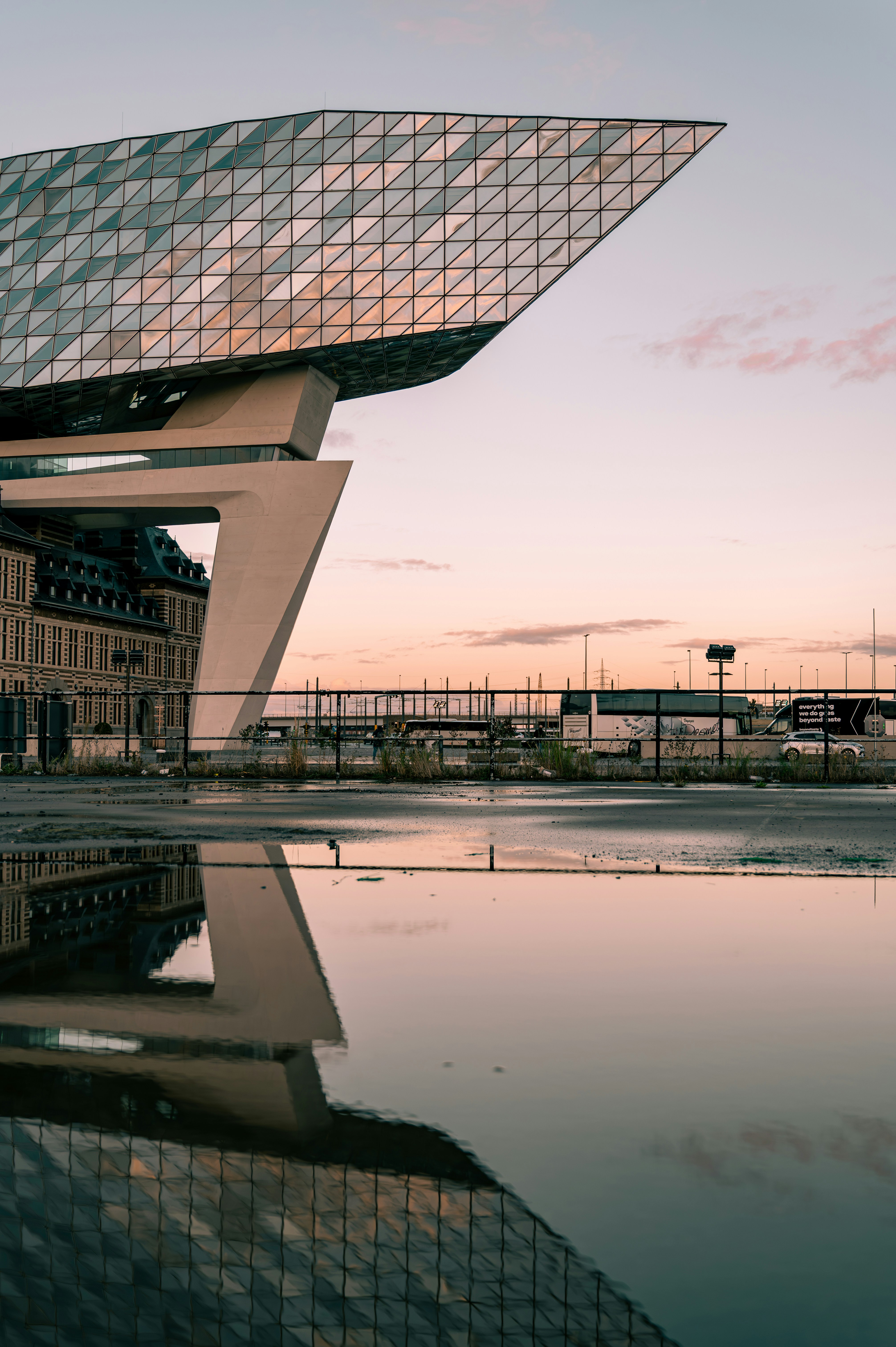 Modern building reflecting in water at sunset
