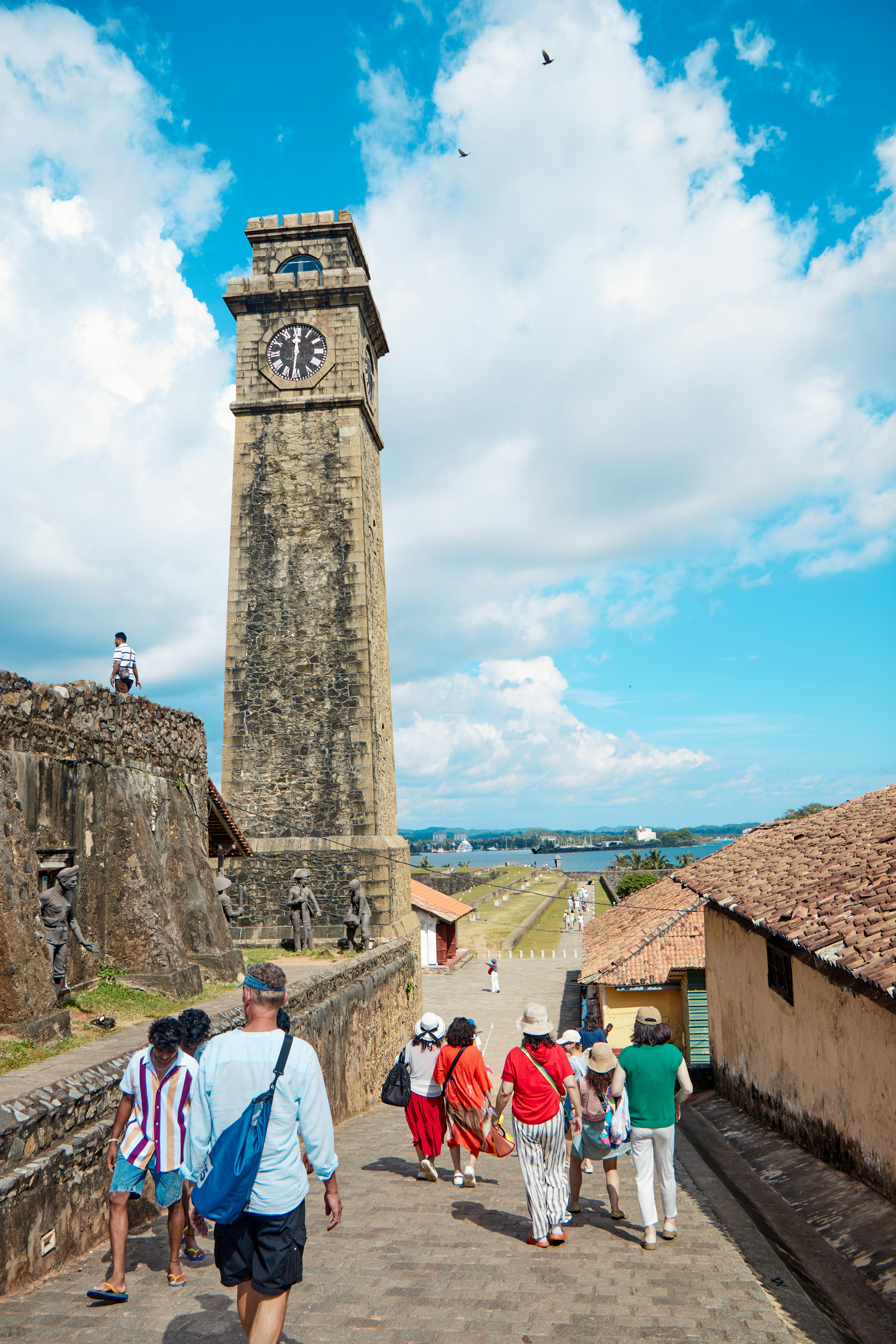 People walk up stone steps towards a clock tower.