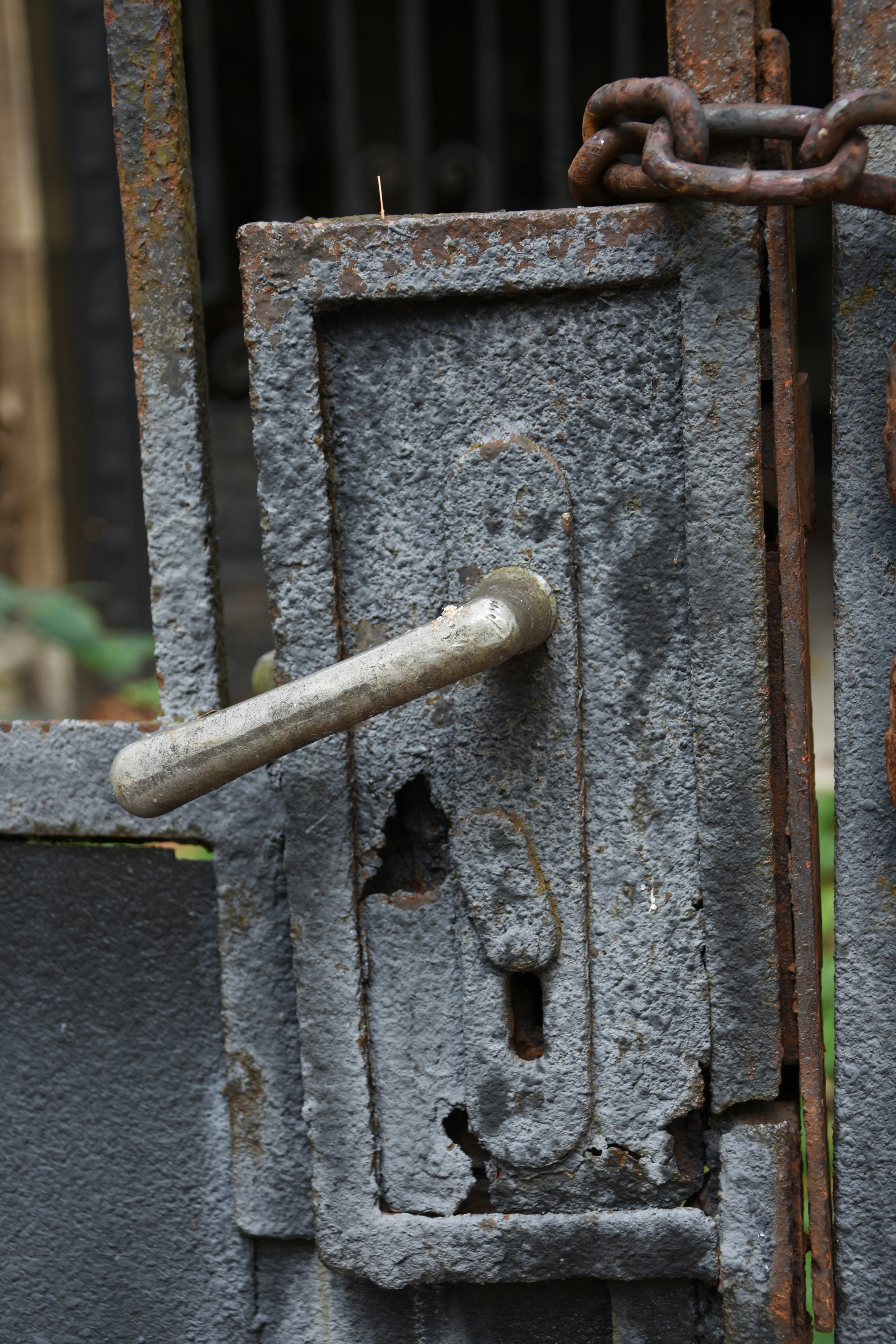 Rusty metal gate with a chain and handle
