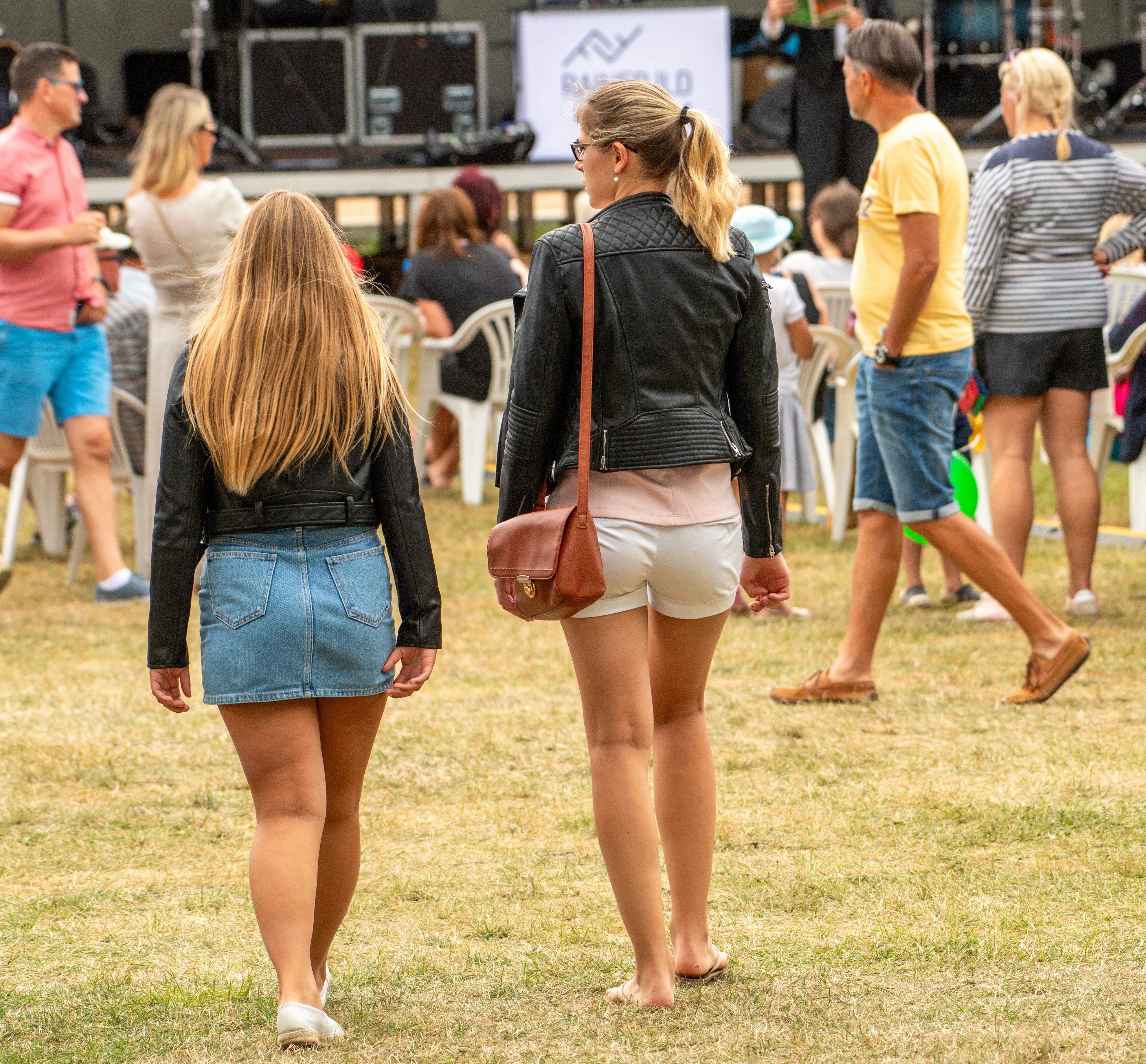 Two women walk across a grassy field.