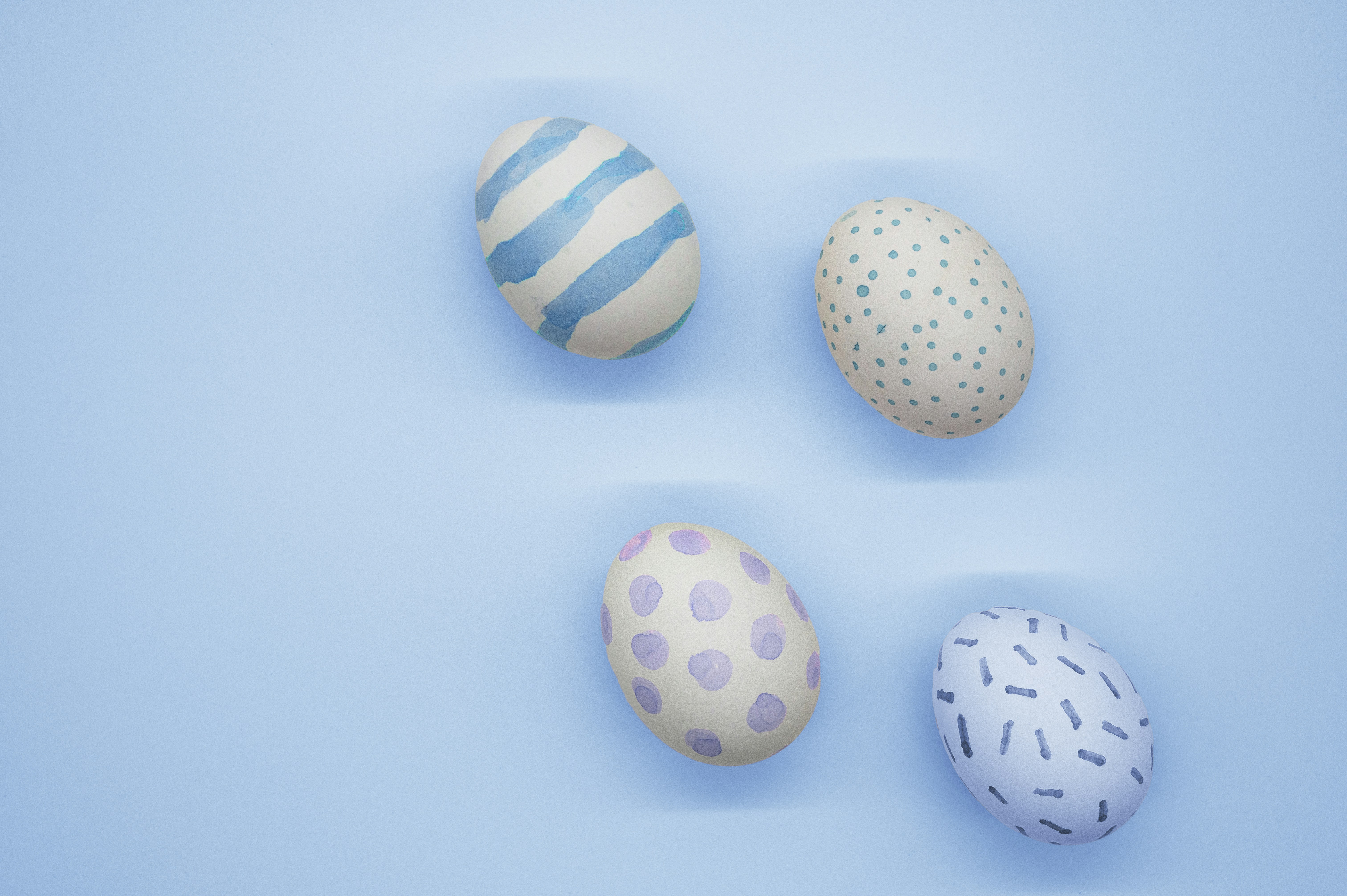 Four decorated easter eggs on a blue background.