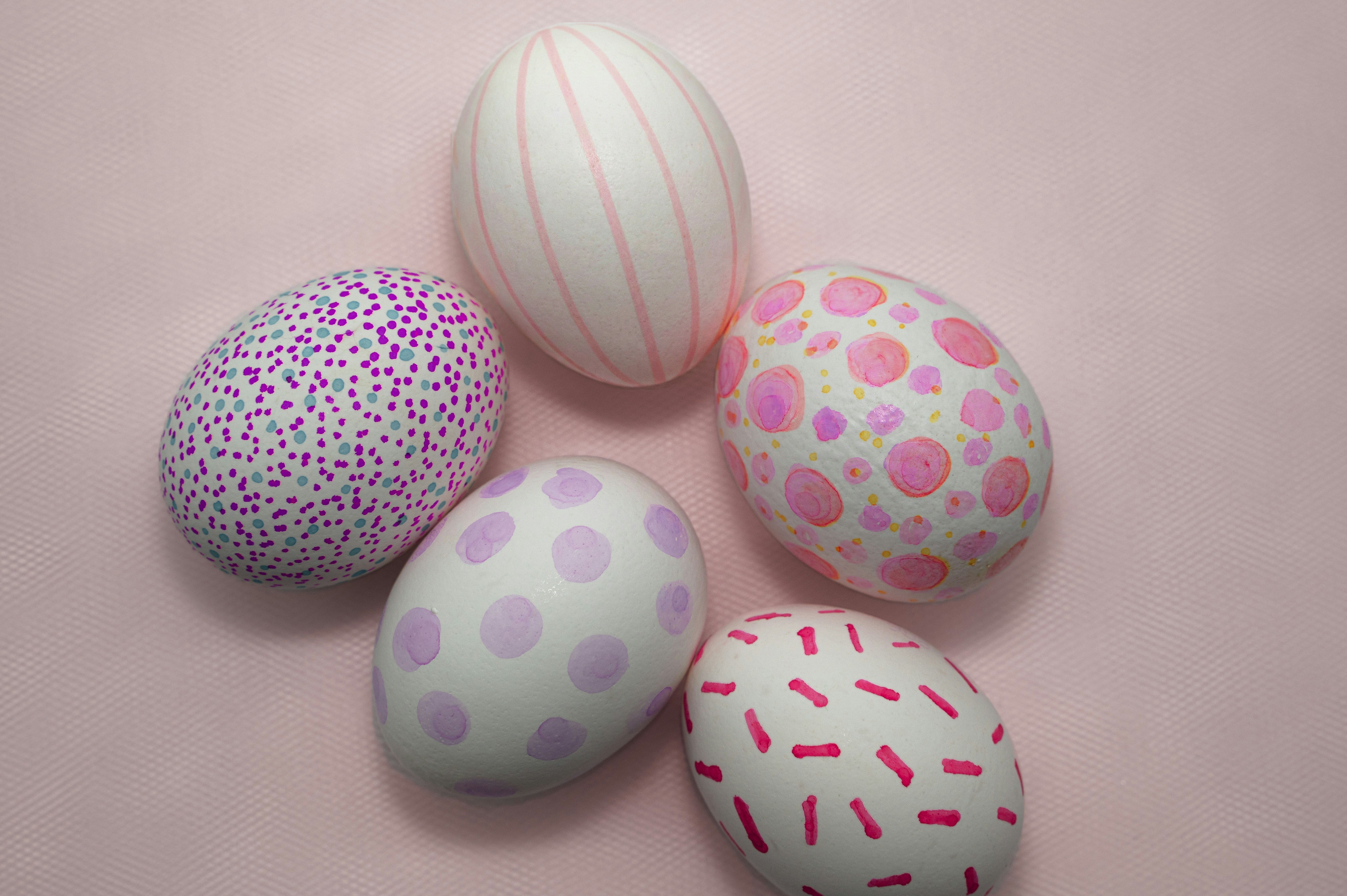 Five decorated easter eggs on a pink background