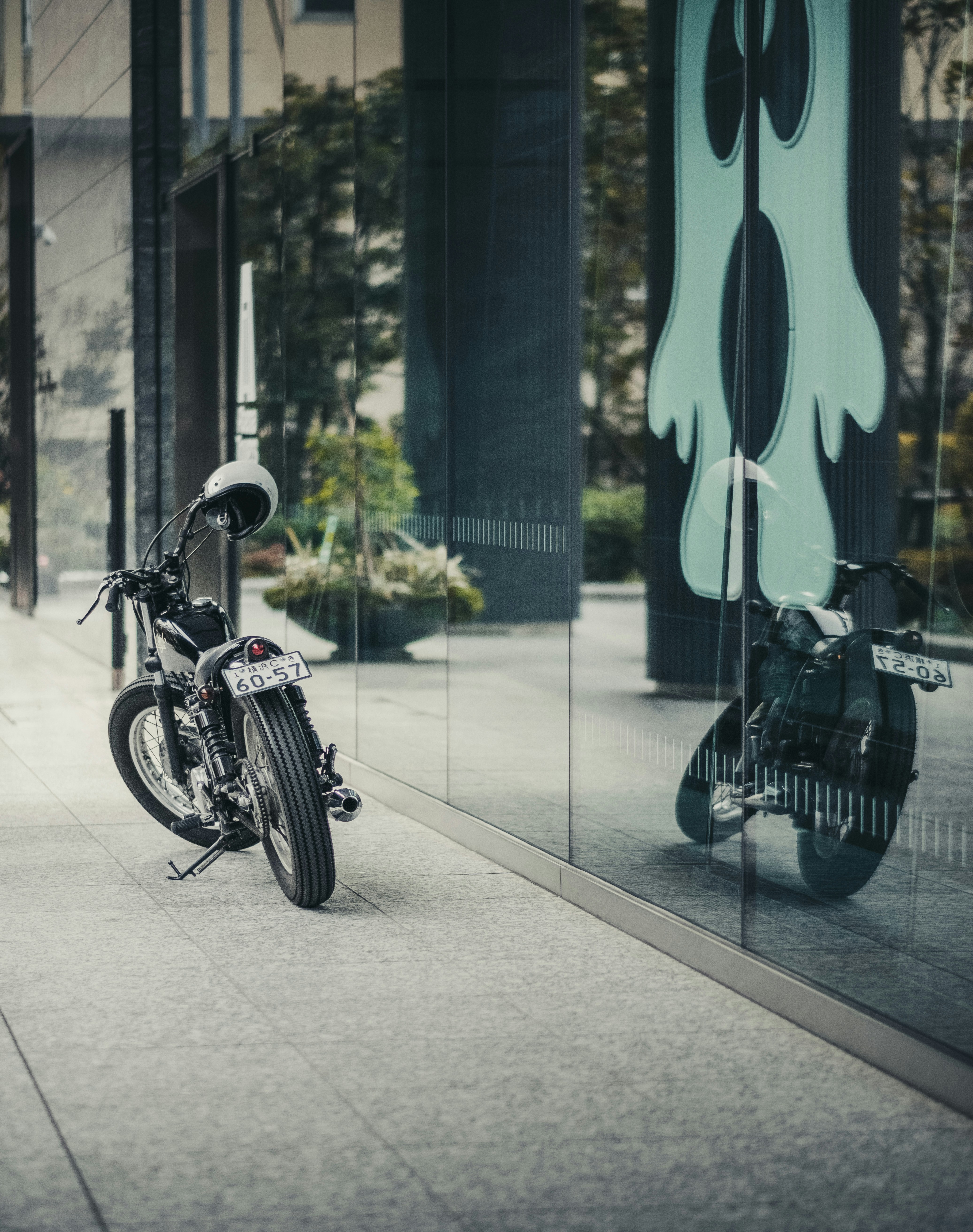 Motorcycle parked outside a modern building with reflection