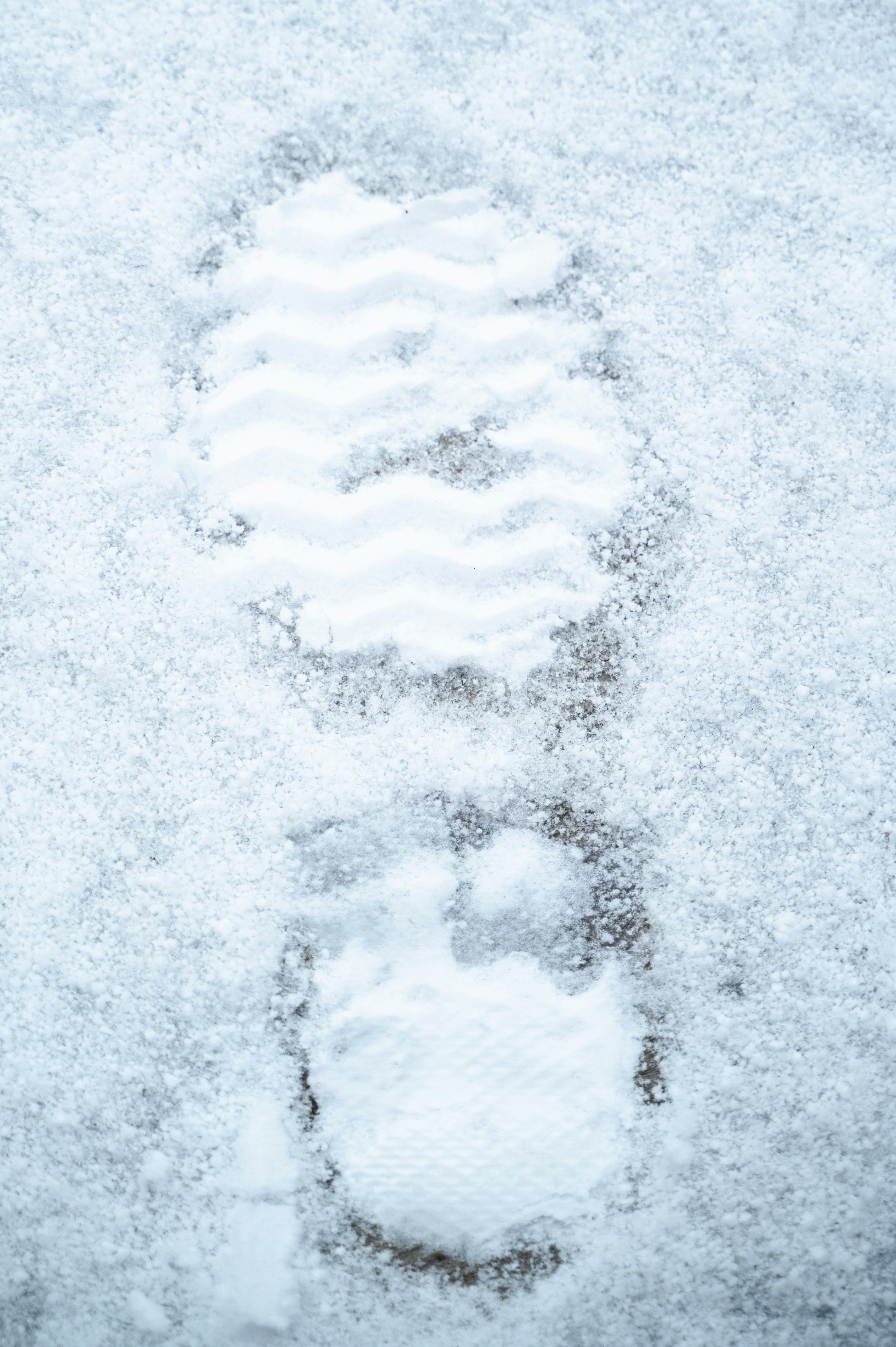 A footprint in the snow with a clear tread pattern.