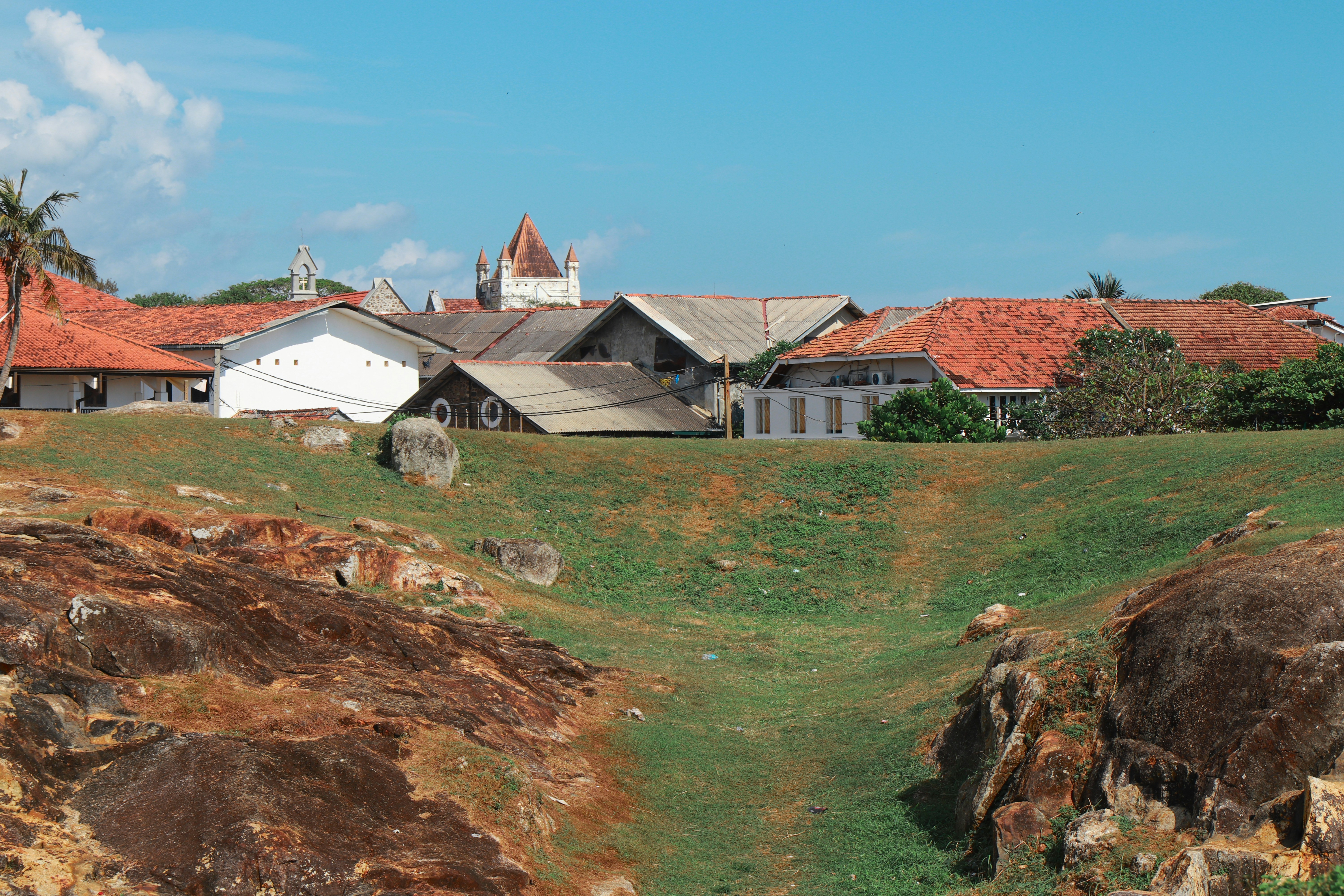 Old buildings with red tile roofs under a blue sky.