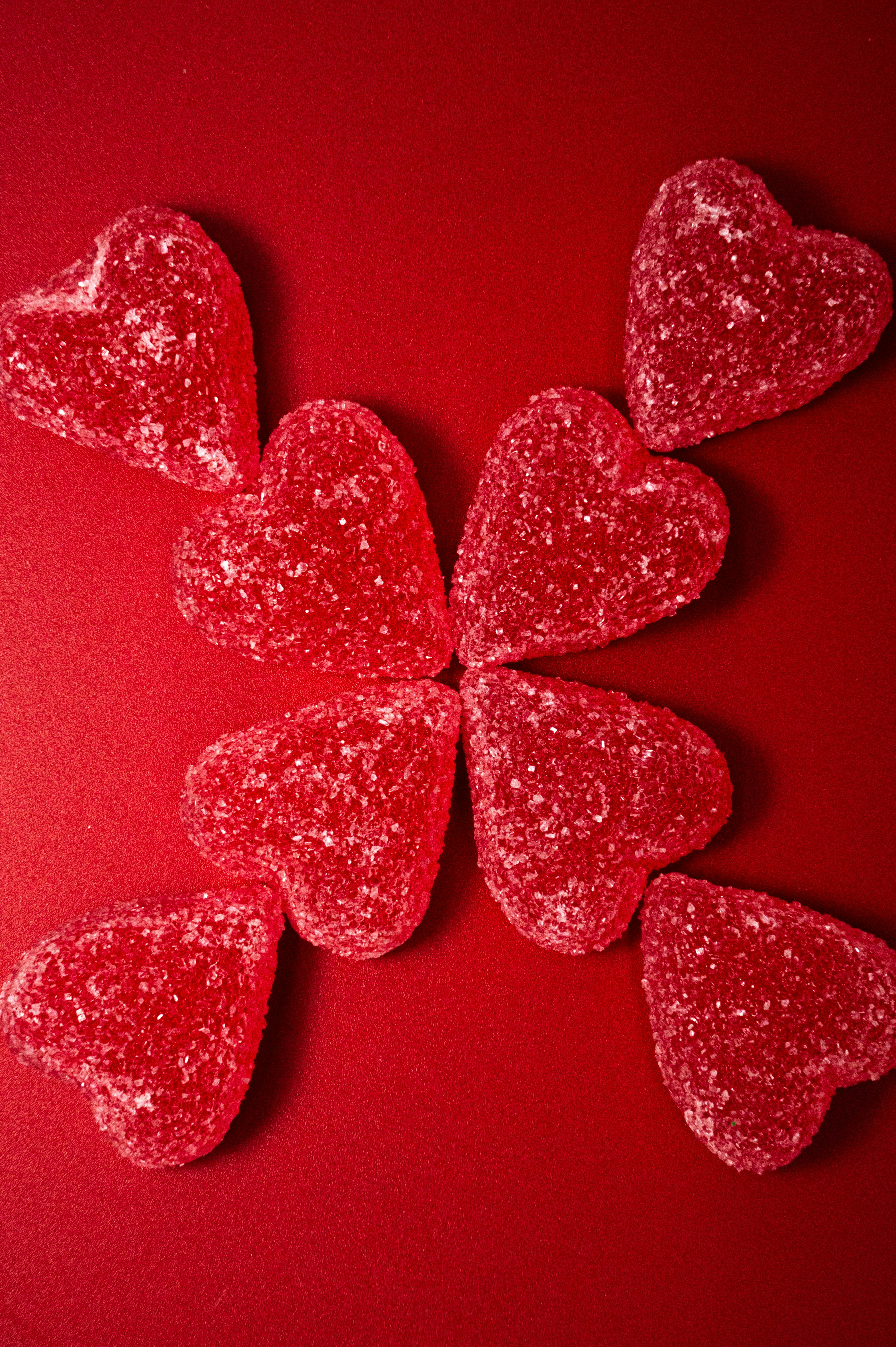 Caramelle rosse a forma di cuore disposte su sfondo rosso