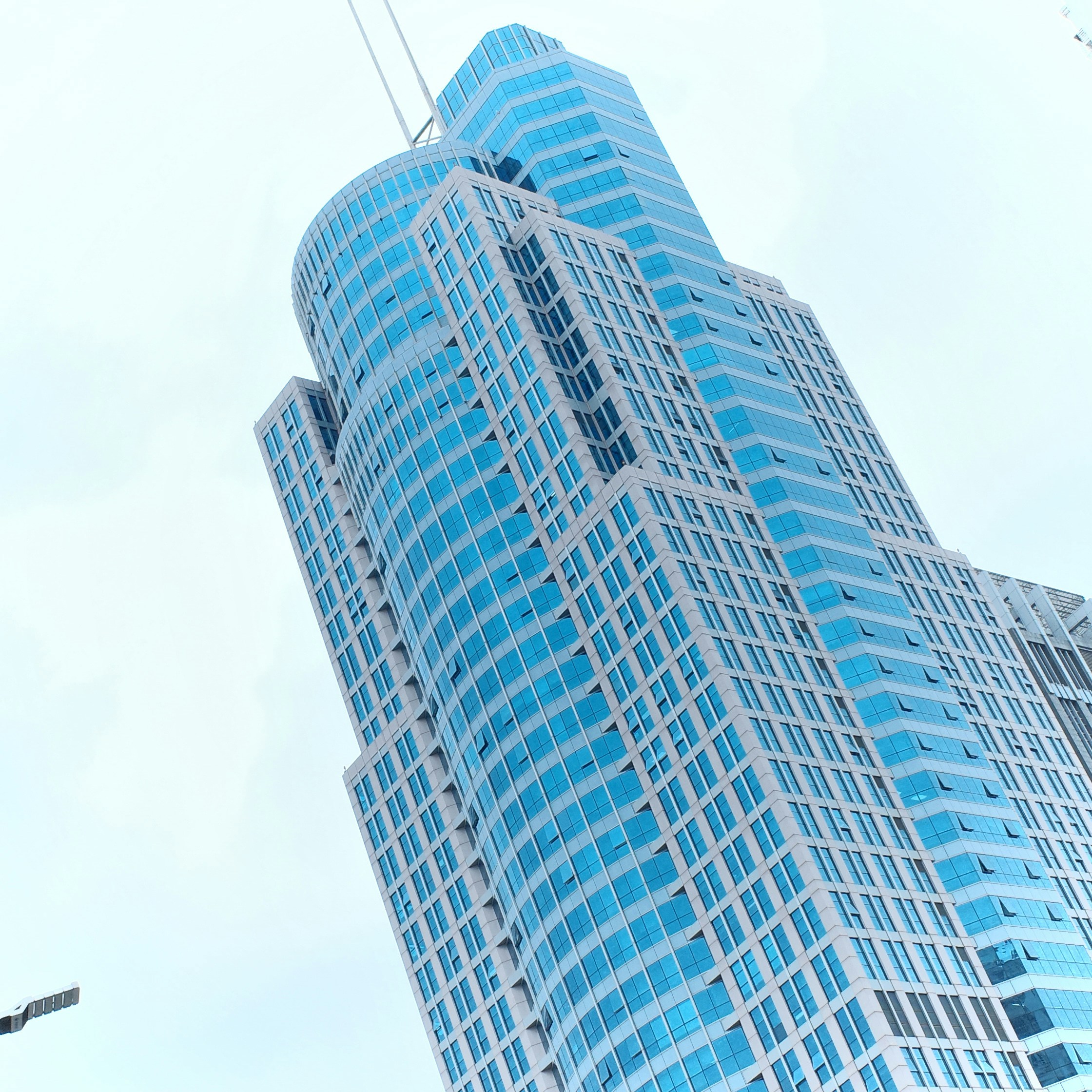 Gratte-ciel moderne avec façade en verre bleu sur un ciel nuageux