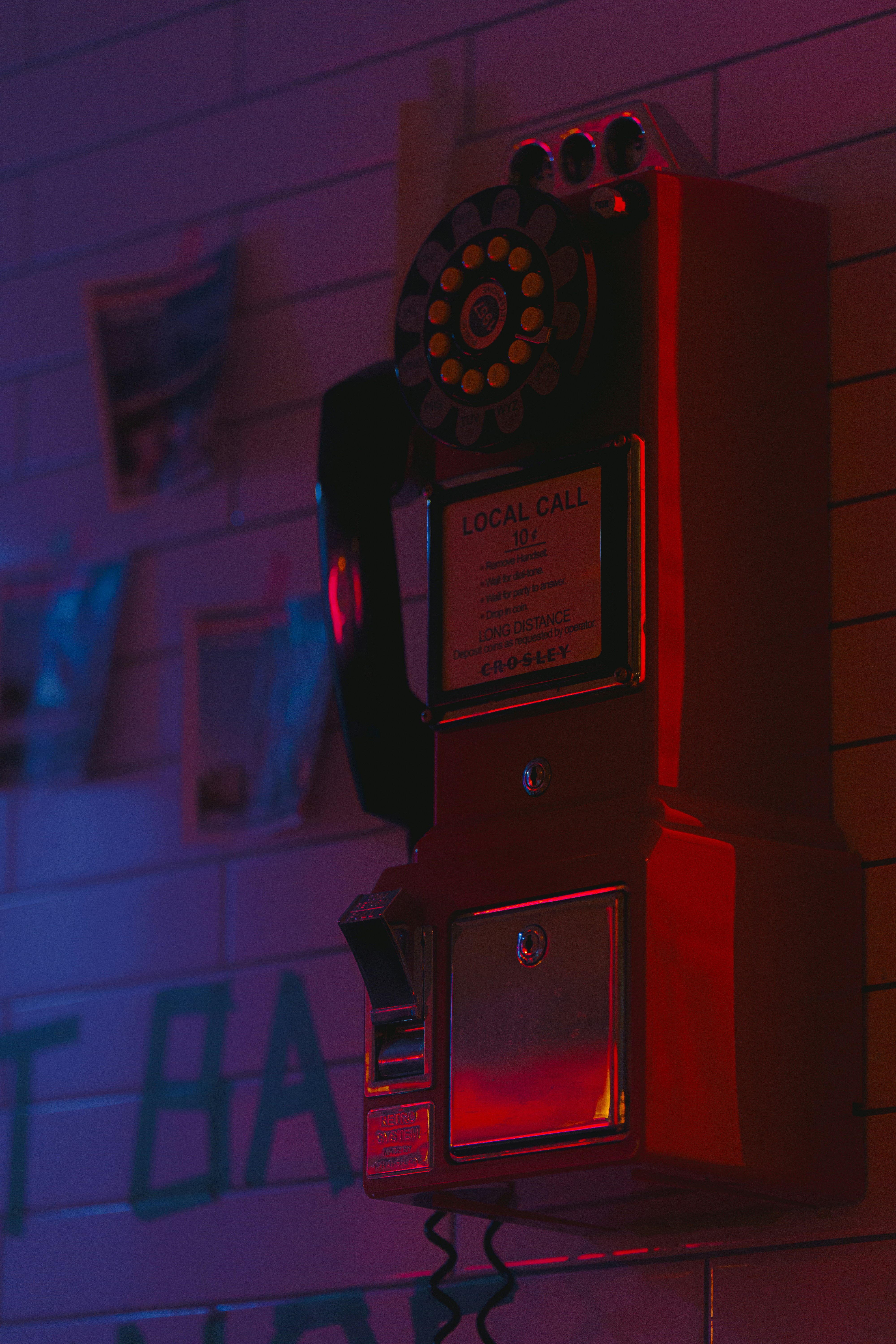 Red vintage payphone mounted on a tiled wall.