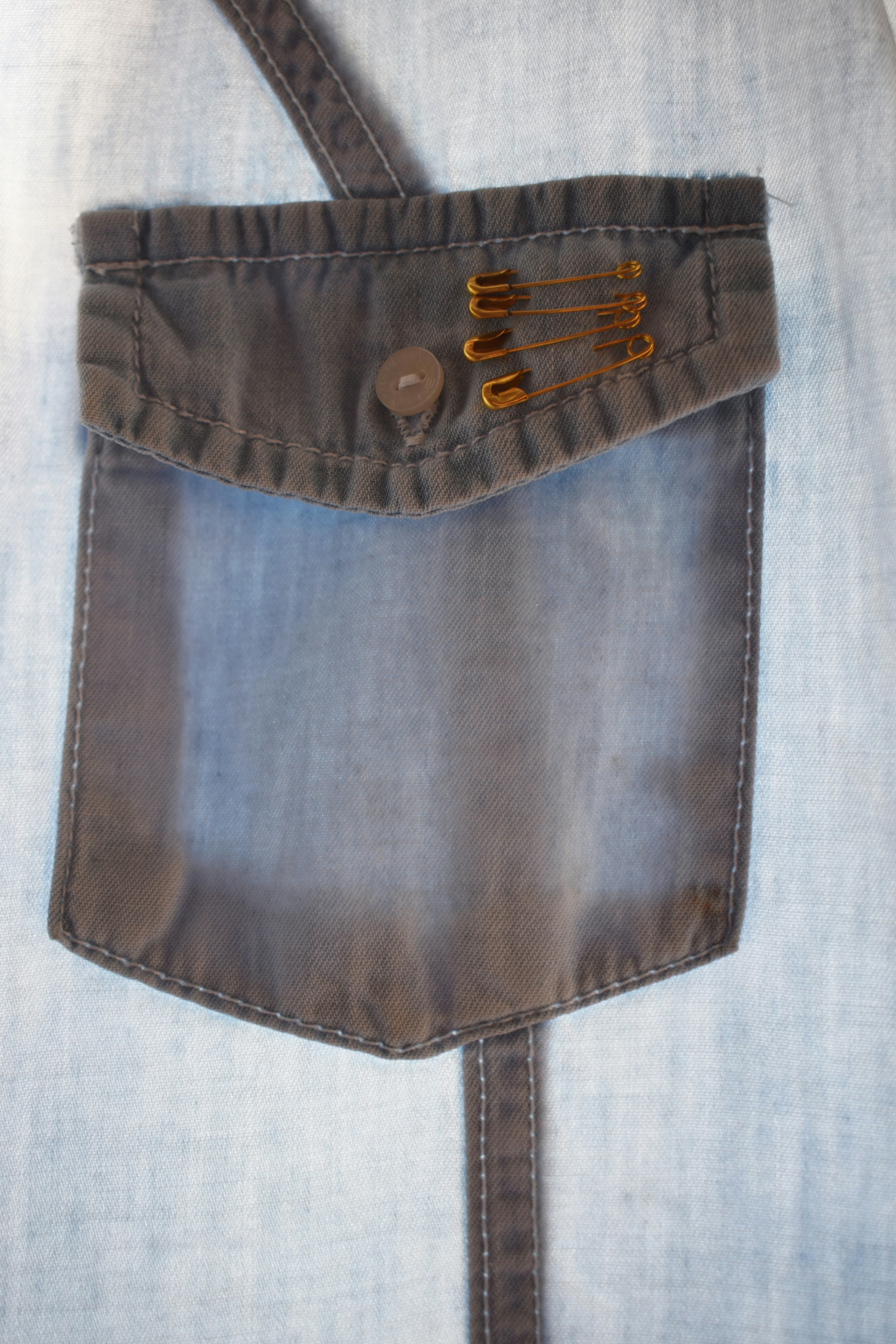Denim pocket with safety pins and button