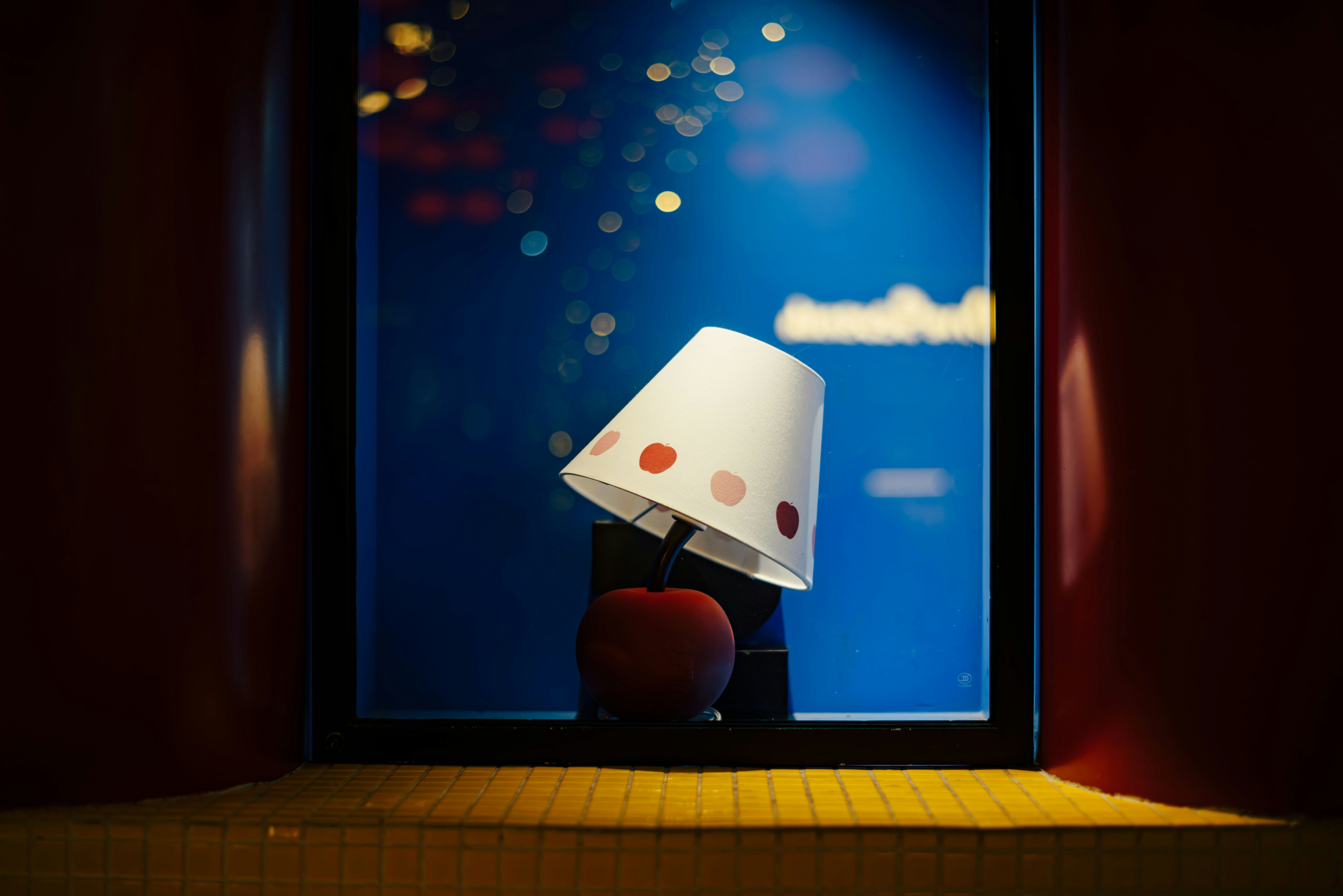 Red apple and lamp with polka dots by window